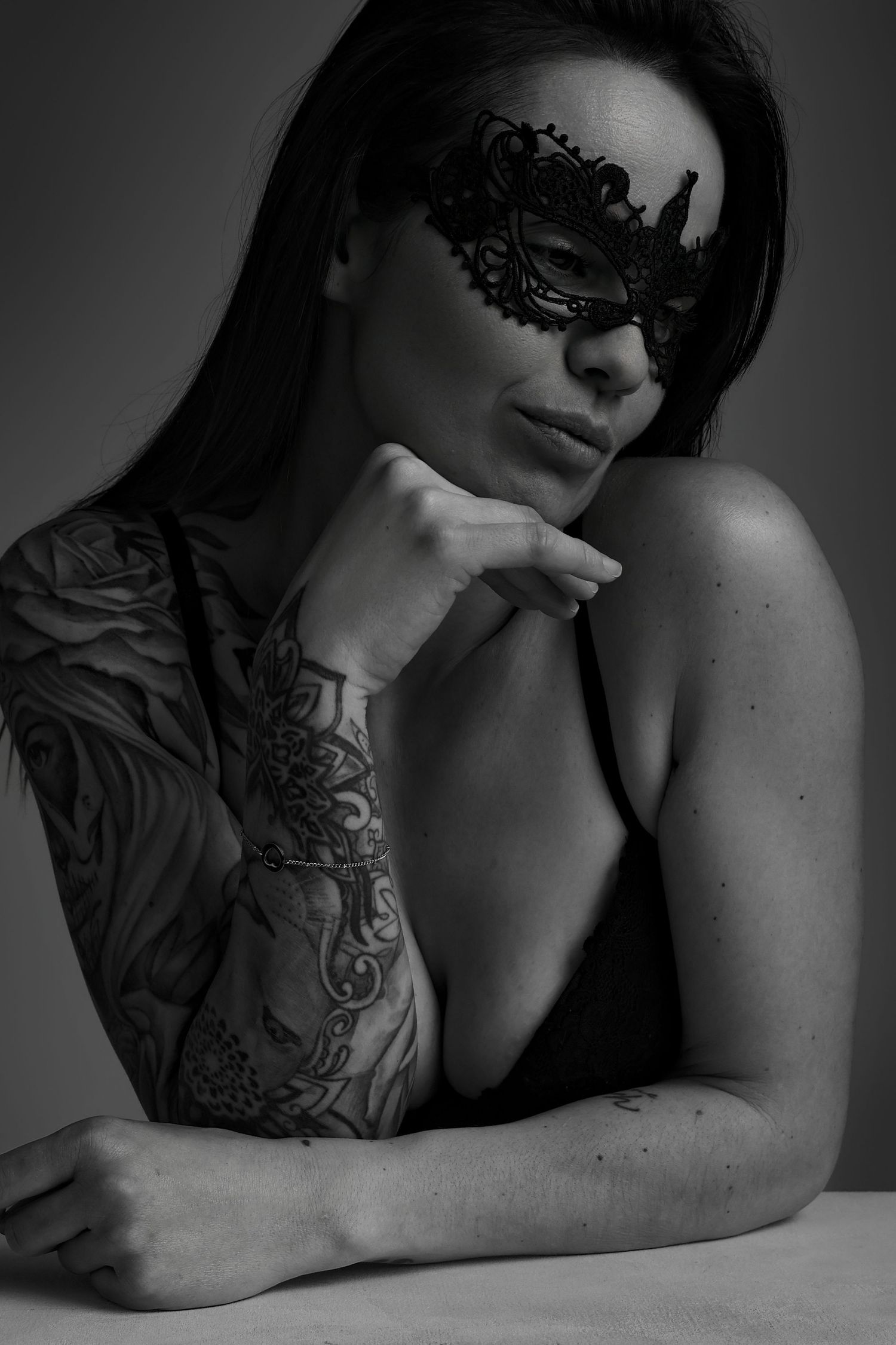 Femme en masque de dentelle noire avec tatouage, portrait boudoir