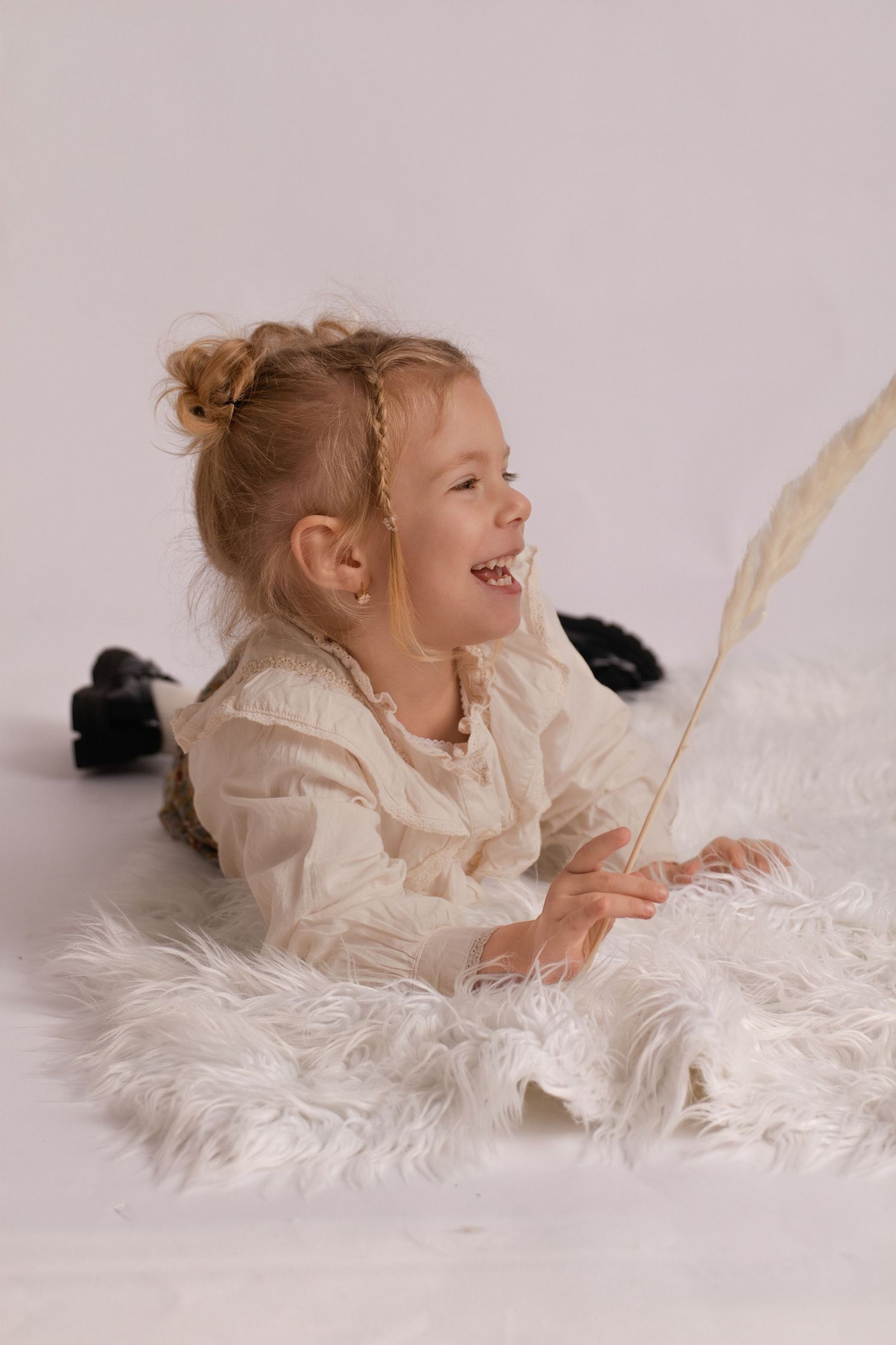 Bébé qui sourit aux éclats lors d'une séance photo studio à Septvaux. Portrait d'enfant avec bonnet et wrap par Cindy Poulet, près de Chauny