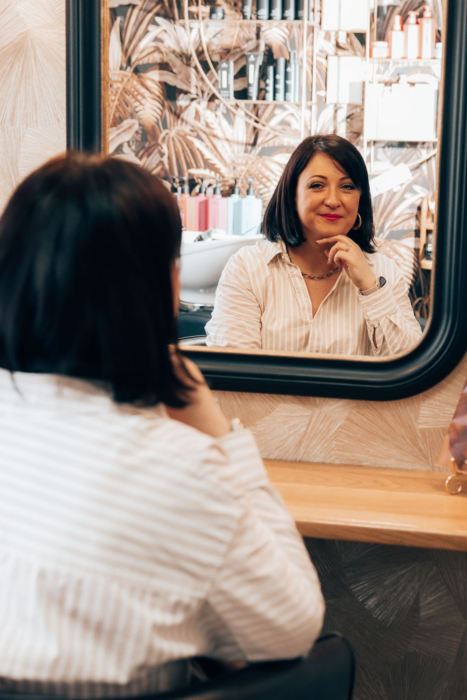 Reflet d'une femme souriante dans le miroir d'un salon de coiffure, par Cindy Poulet Photographe proche Saint Quentin.