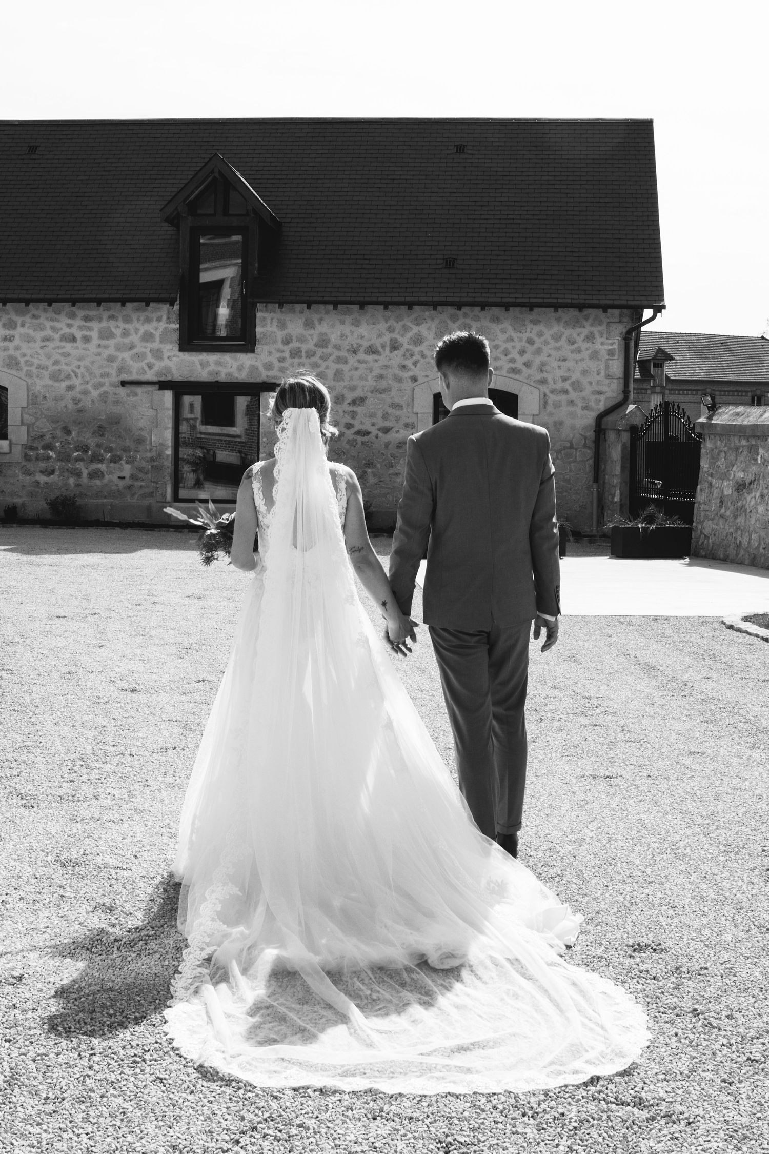 Mariée en robe blanche marchant main dans la main avec le marié, photo de mariage noir et blanc