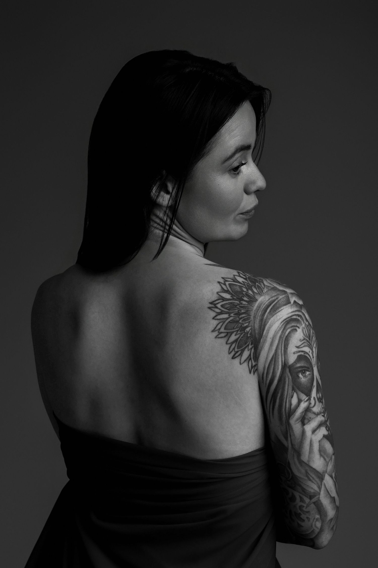 Portrait de femme de dos montrant tatouage sur épaule, noir et blanc