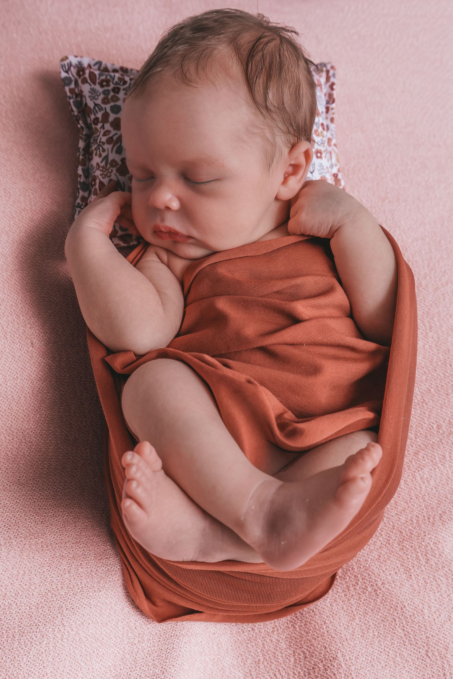 Bébé nouveau-né endormi dans un nid en tissu rose, séance photo naissance - Cindy Poulet photographe