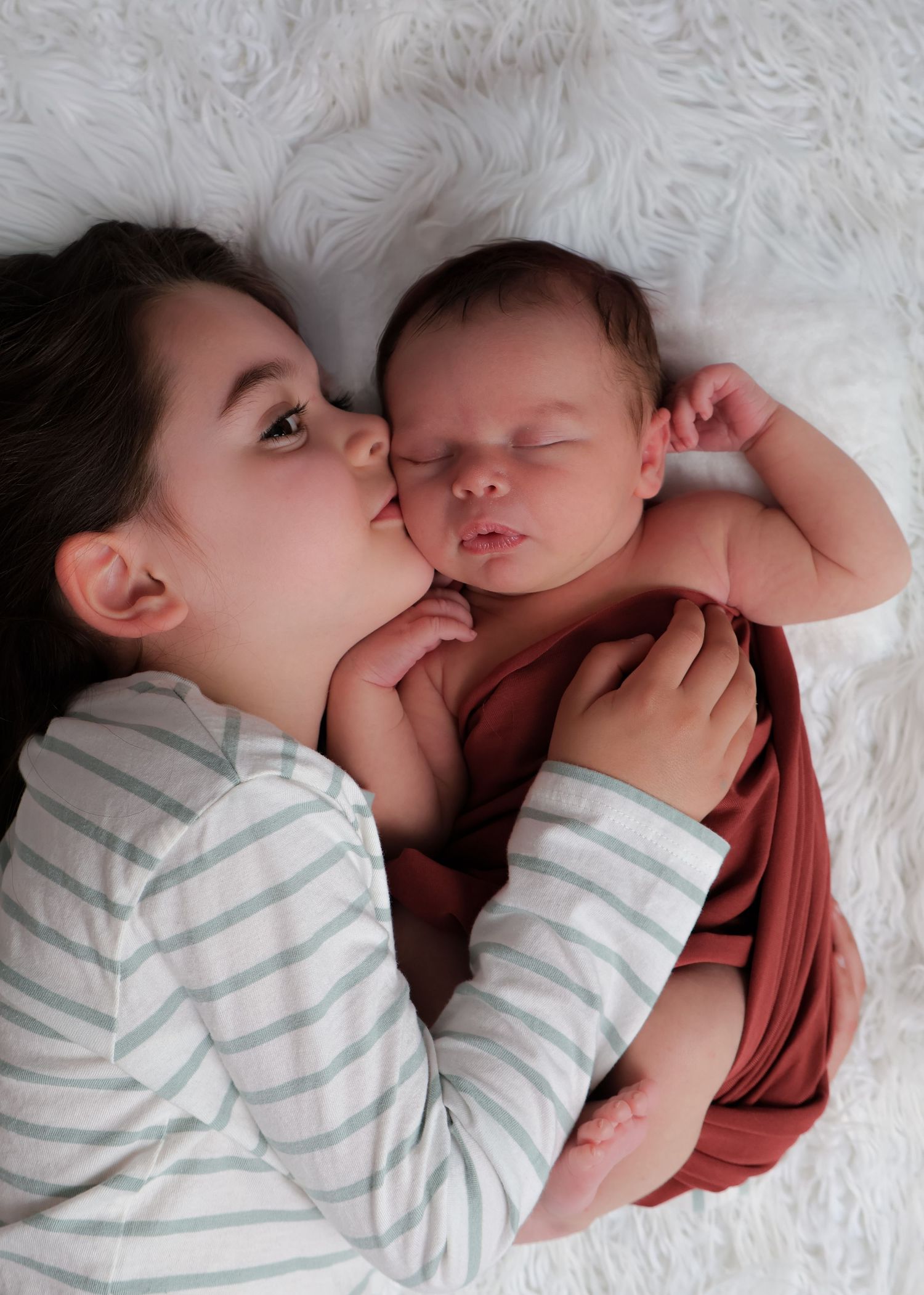 Grand enfant faisant un câlin et bisou à son petit frère nouveau-né - Cindy Poulet photographe