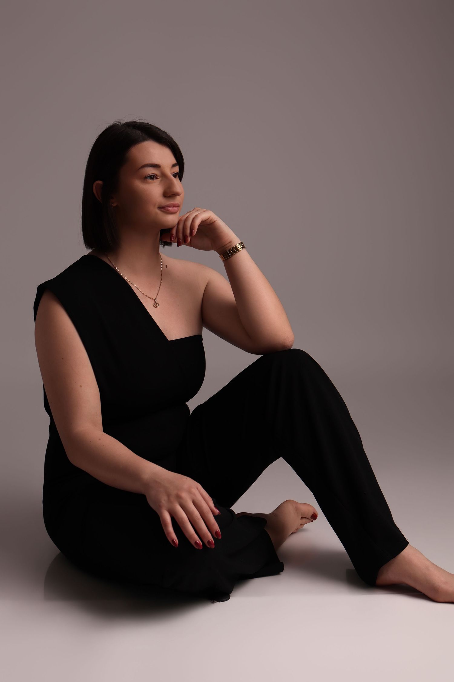 Femme en tenue noire élégante assise, portrait en studio