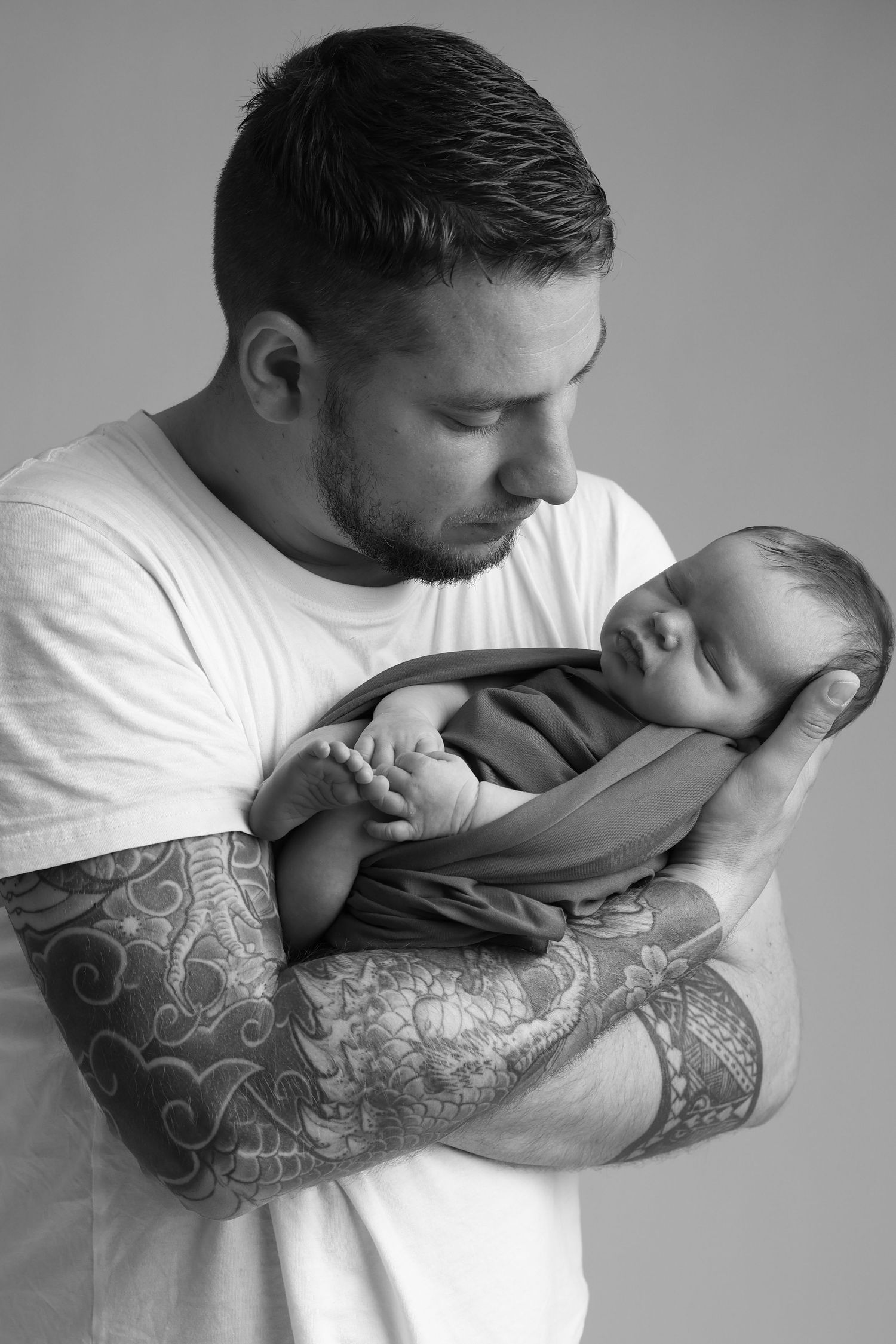 Papa tatoué tenant son nouveau-né dans les bras, séance photo naissance - Cindy Poulet photographe