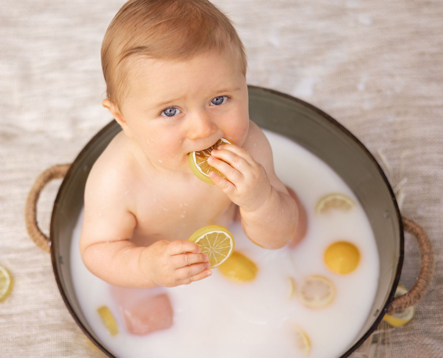 Séance photo bébé bain de lait par Cindy Poulet Photographe : portrait d'un enfant aux yeux bleus dans une bassine en métal.