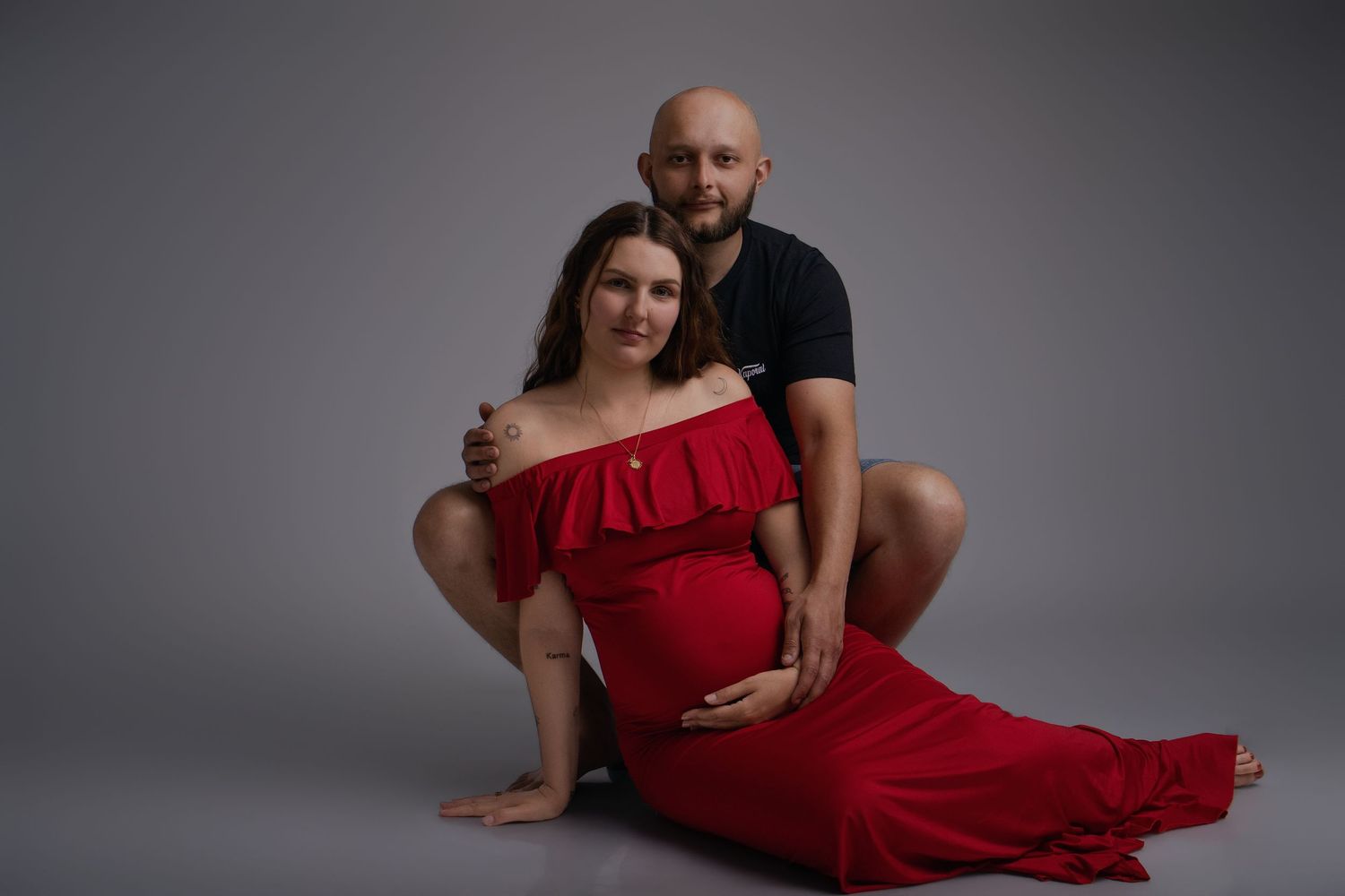 Couple complice en séance photo maternité studio, femme en robe rouge - Cindy Poulet photographe