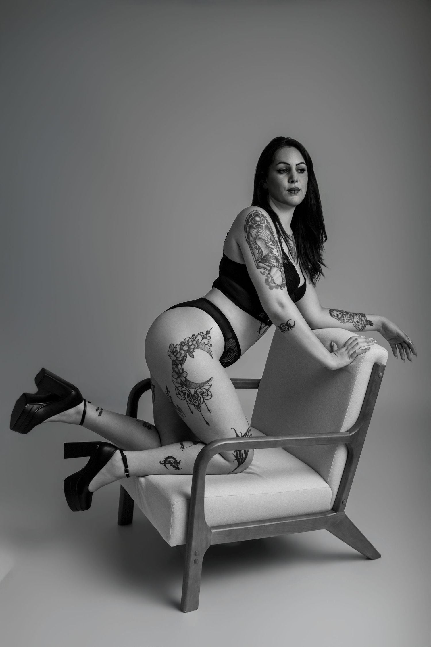 Femme tatouée posant à genoux sur une chaise en noir et blanc - Cindy Poulet photographe