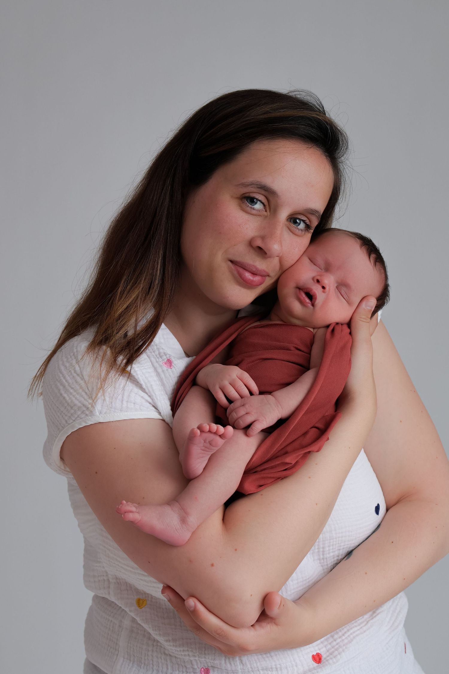Maman souriant en tenant son nouveau-né dans les bras, séance naissance