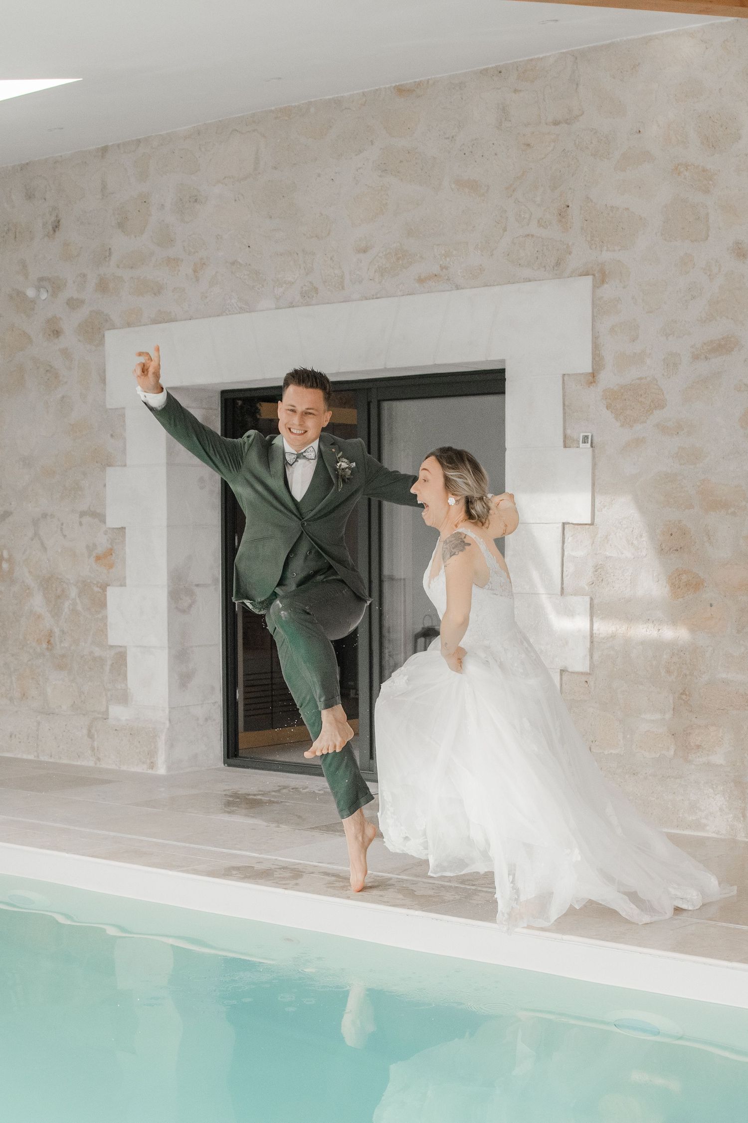 Couple de mariés sautant joyeusement au bord d'une piscine - Cindy Poulet photographe