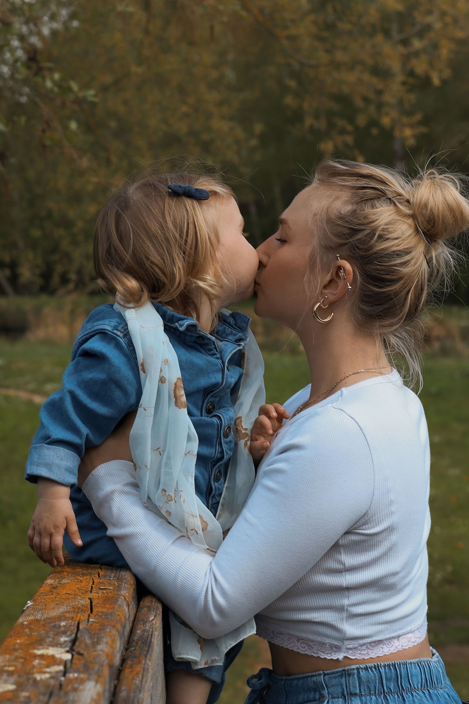 Maman embrassant son bébé dans les bras dans un parc en automne