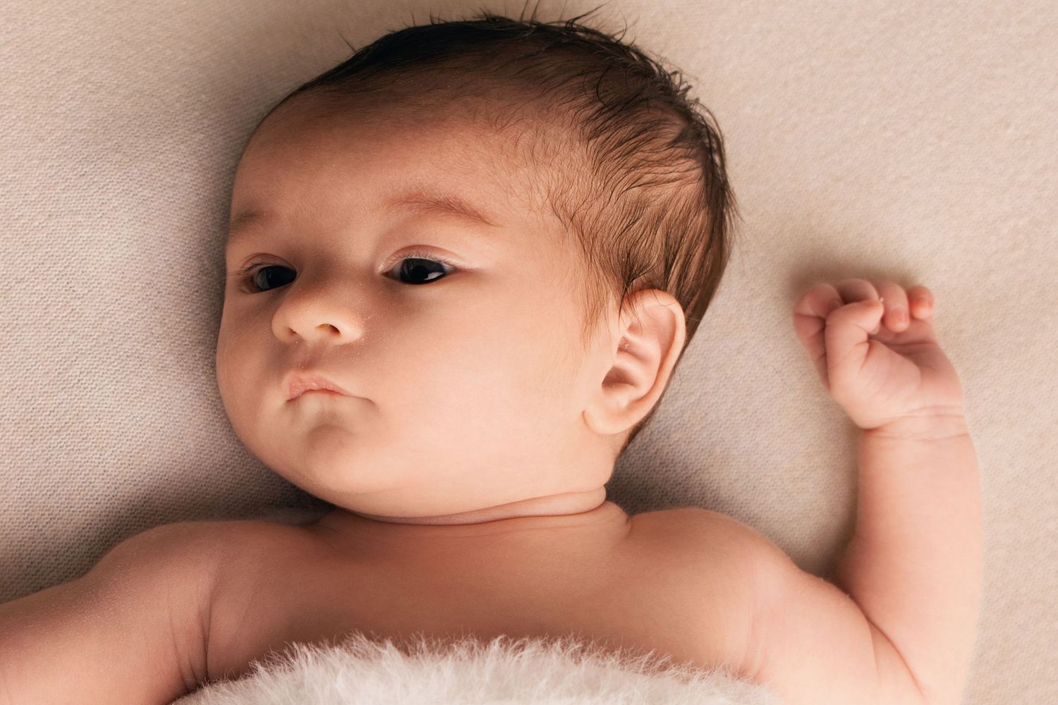 Photographie de nouveau-né par Cindy Poulet Photographe : portrait d'un bébé éveillé aux tons chauds et naturels lors d'une séance photo nai