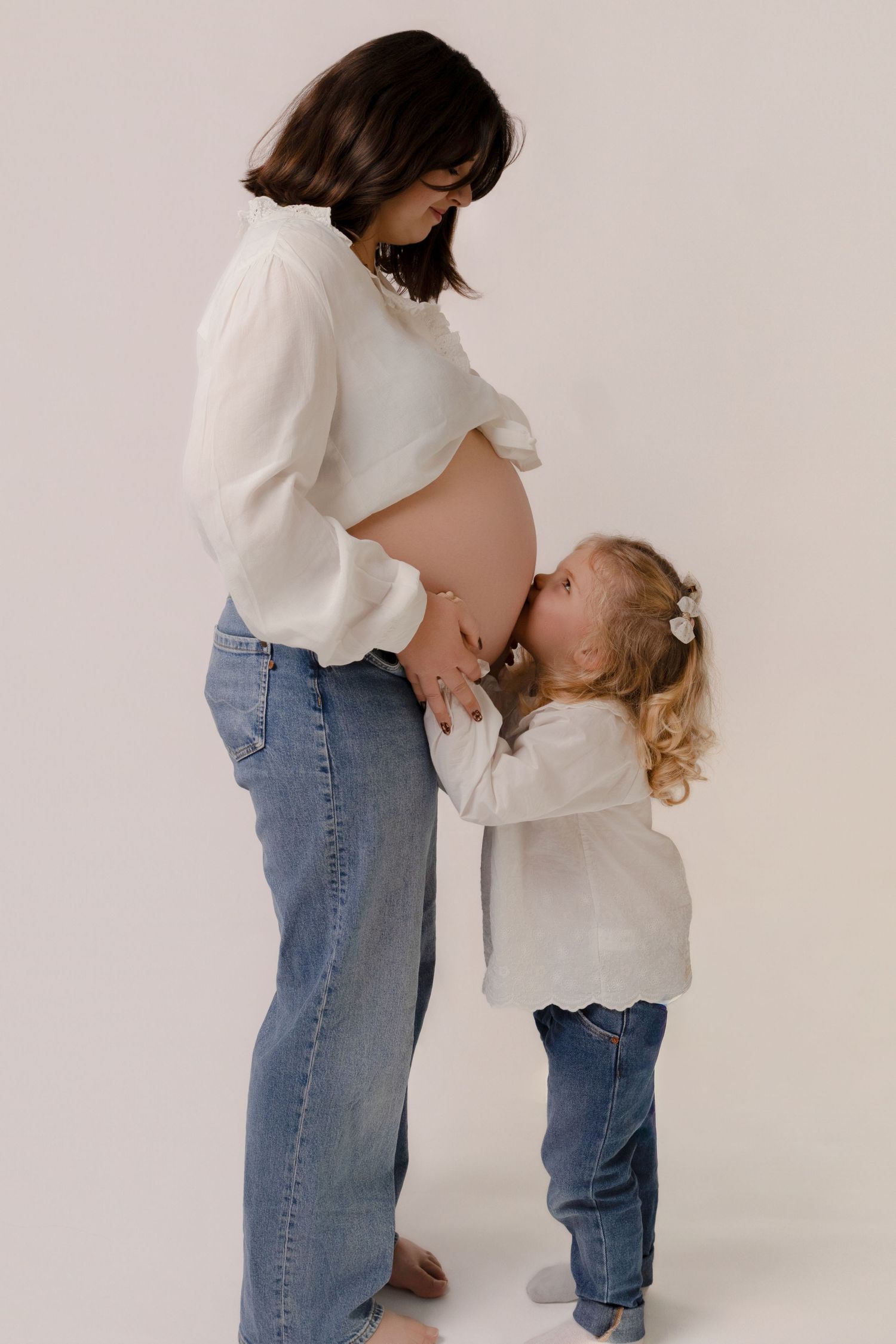 Petite fille embrassant le ventre de sa maman enceinte, séance photo maternité et famille en studio par Cindy Poulet Photographe
