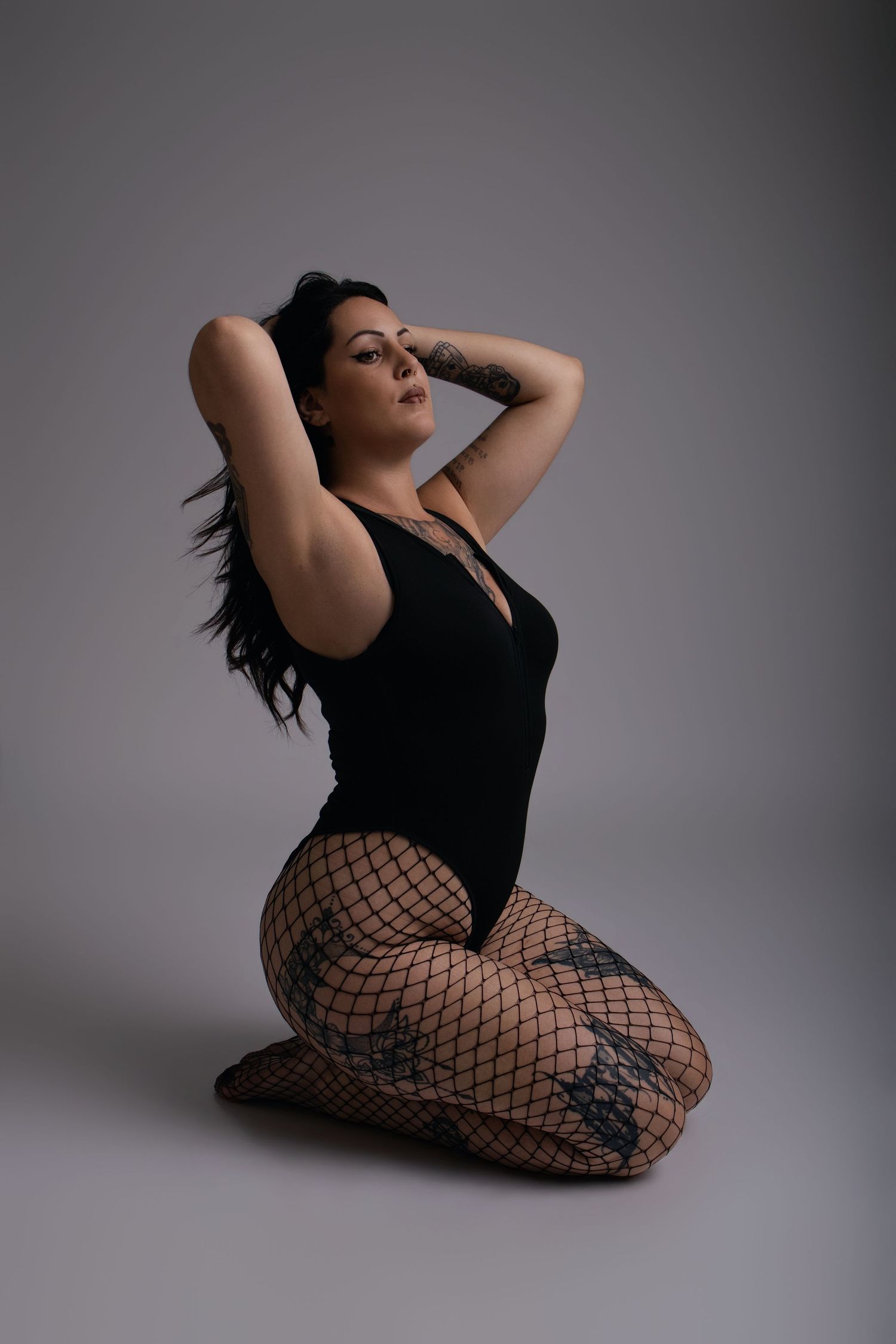 Femme en body noir à genoux les mains dans les cheveux, portrait studio - Cindy Poulet photographe