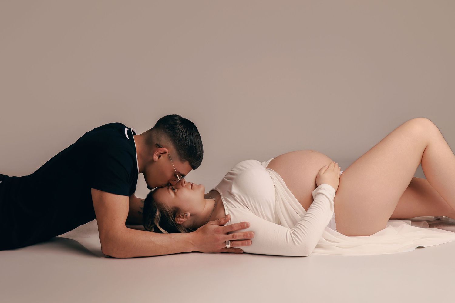 Femme enceinte en robe longue beige élégante, séance photo maternité en studio