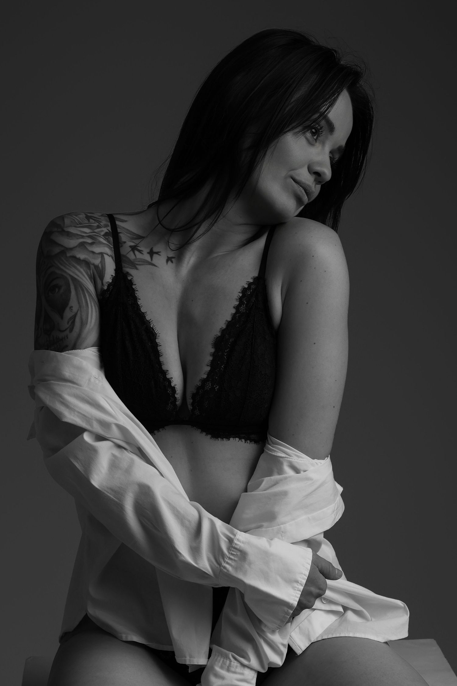Femme en lingerie noire déboutonnant chemise blanche, portrait boudoir
