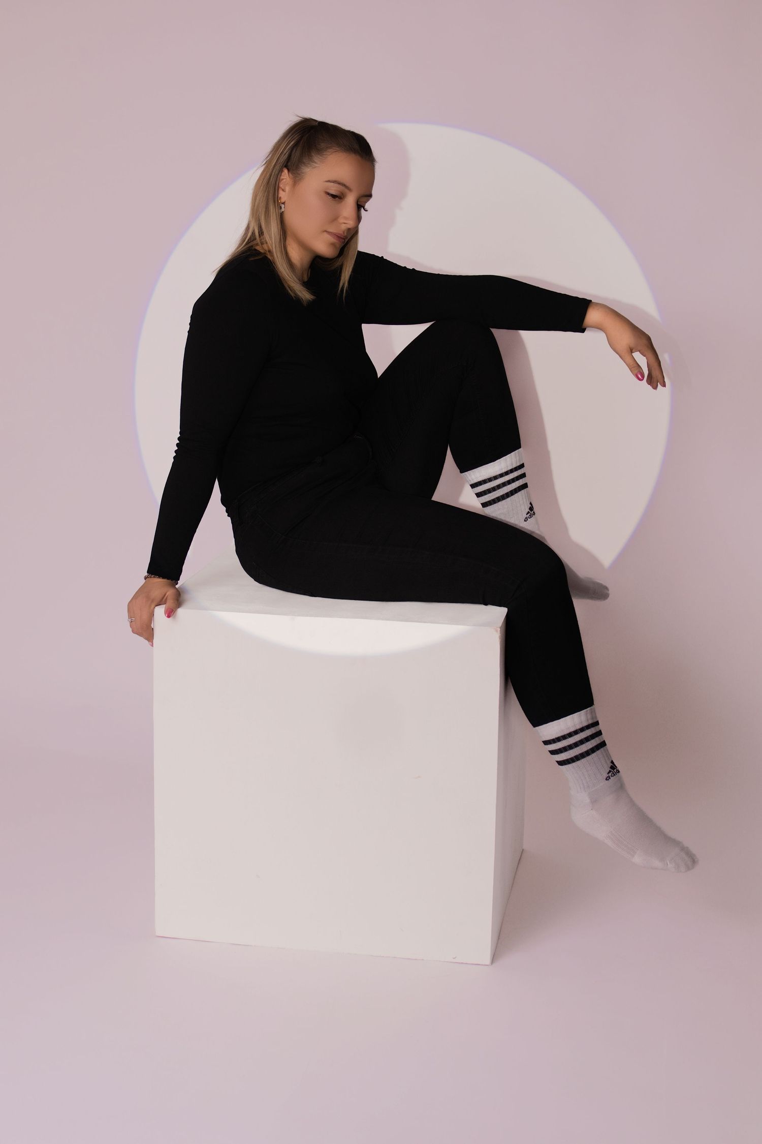 Portrait studio d'une femme assise sur un cube blanc en tenue noire, par Cindy Poulet Photographe proche Soissons.