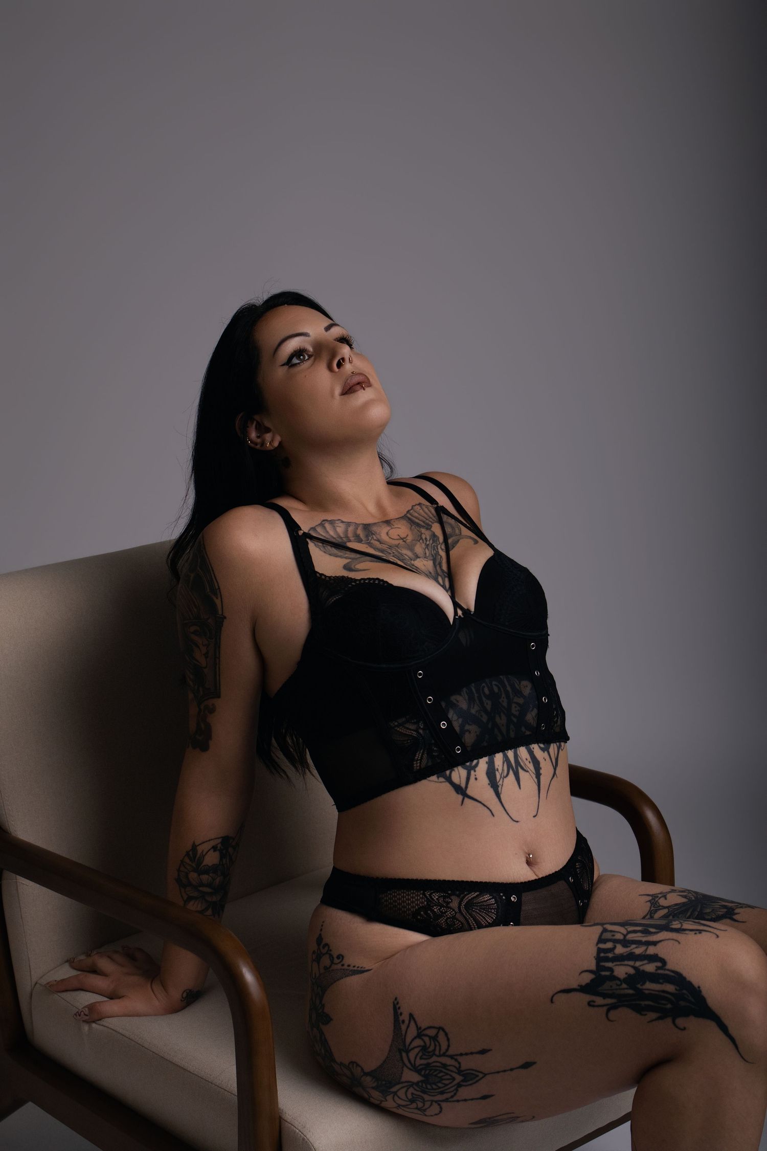 Femme tatouée en lingerie noire assise dans un fauteuil, boudoir artistique - Cindy Poulet photographe