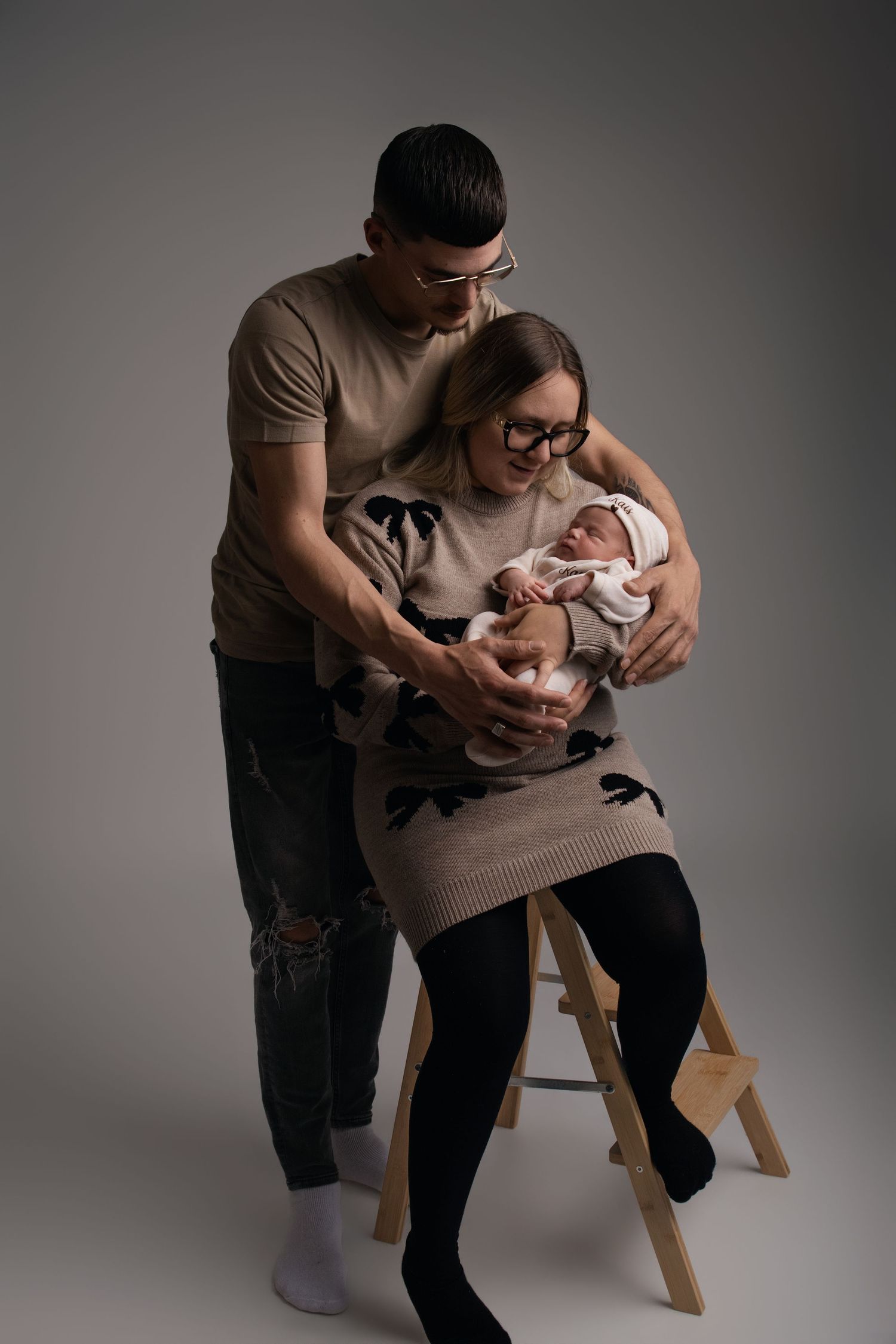Couple assis en studio tenant tendrement leur nouveau-né, séance photo naissance - Cindy Poulet photographe