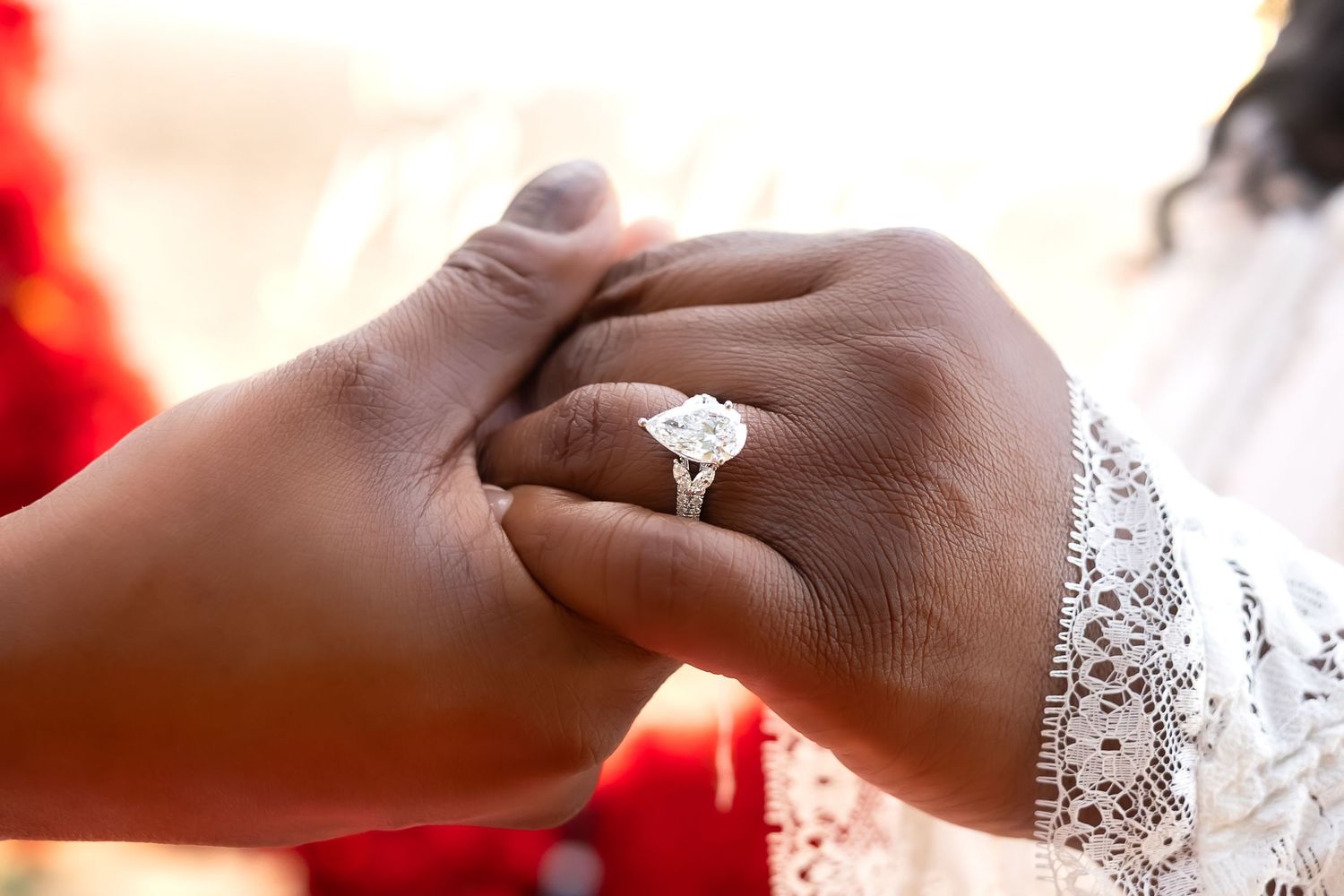 Close-up of elegant pear-shaped diamond engagement ring on womans hand after beach proposal.