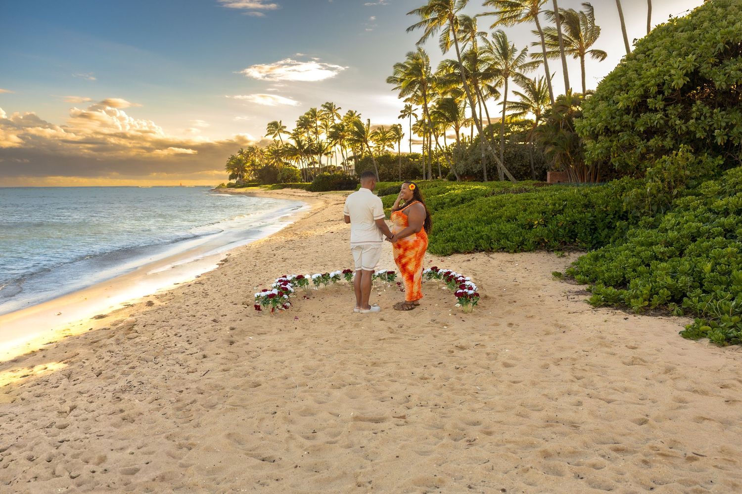 Couple walking hand-in-hand along tropical Hawaiian beach at breathtaking golden sunset.