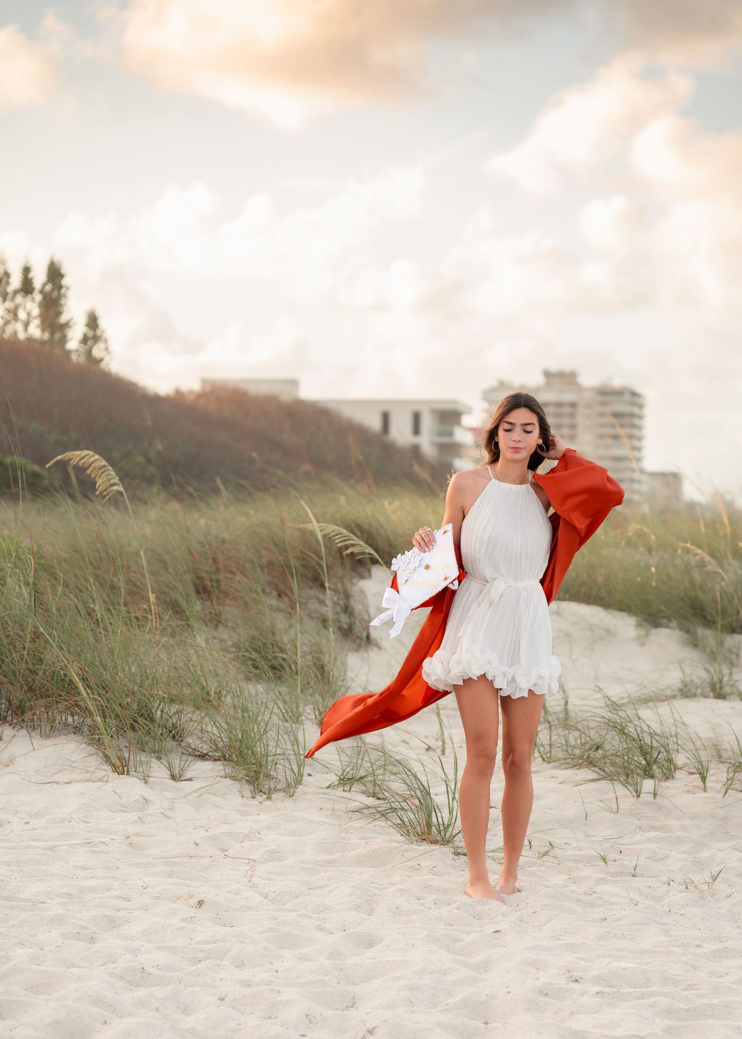 Stunning graduation portrait photography featuring the sandy shoreline and golden sunset at Melbourne Beach with cap and gown.