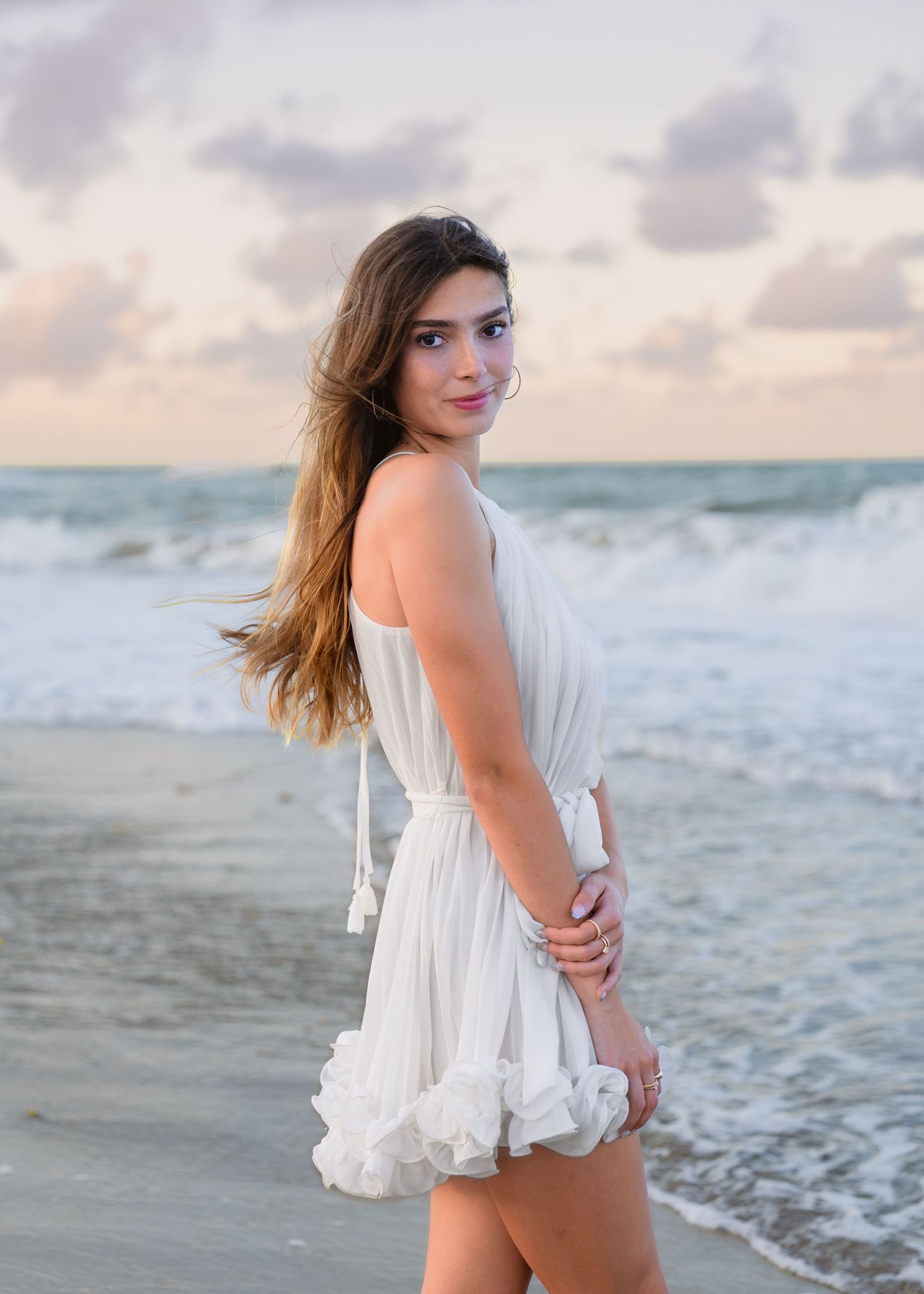 Dreamy graduation portraits captured in the waves beneath the colorful pastel sunset at Melbourne Beach.