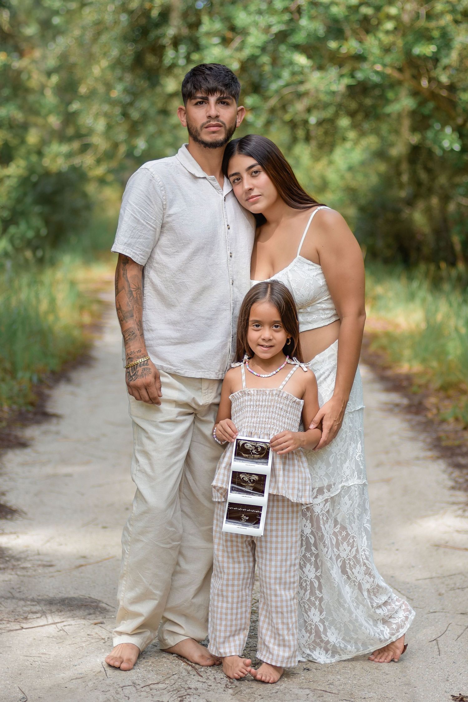 Parents holding ultrasound photos during an outdoor pregnancy announcement session in St. Cloud Florida