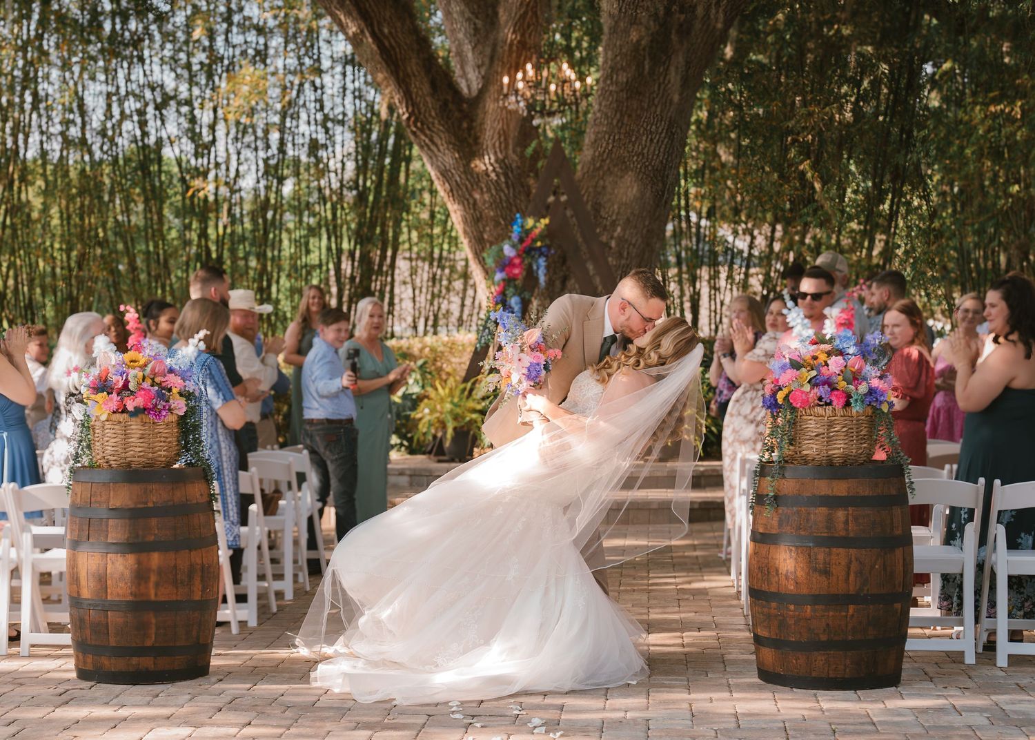 Bride and groom sharing a romantic dip and kiss at the end of the aisle immediately following their outdoor wedding ceremony at Moss Estates