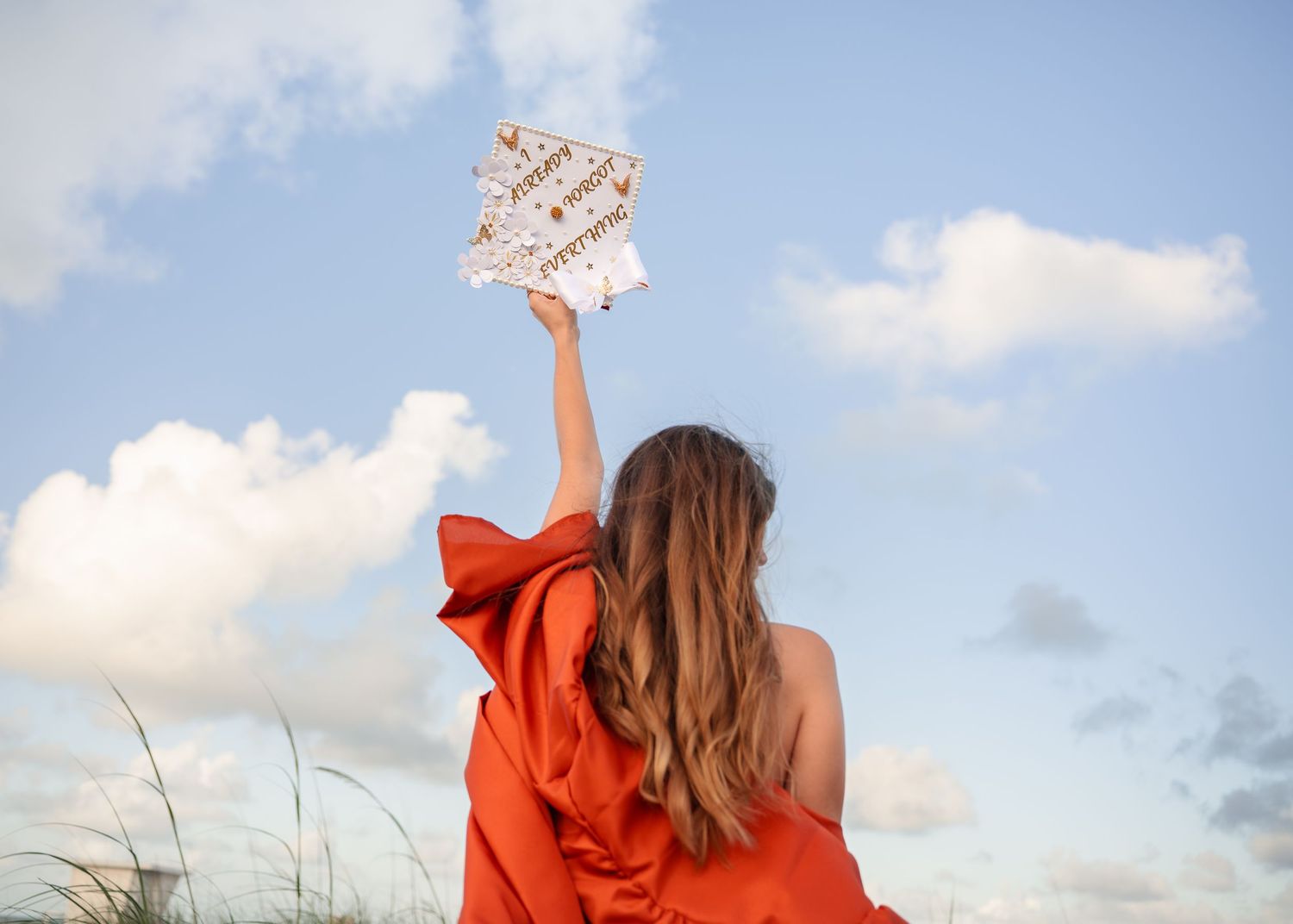 Senior graduation portraits with the beautiful sky at Melbourne Beach, Florida with cap and gown.