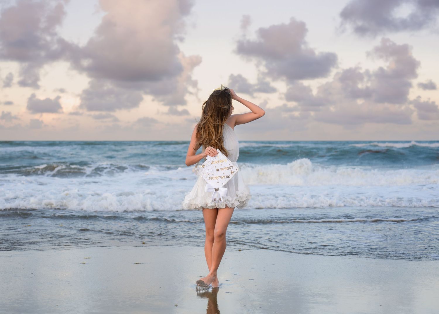 Dreamy graduation portraits captured in the waves beneath the colorful pastel sunset at Melbourne Beach.