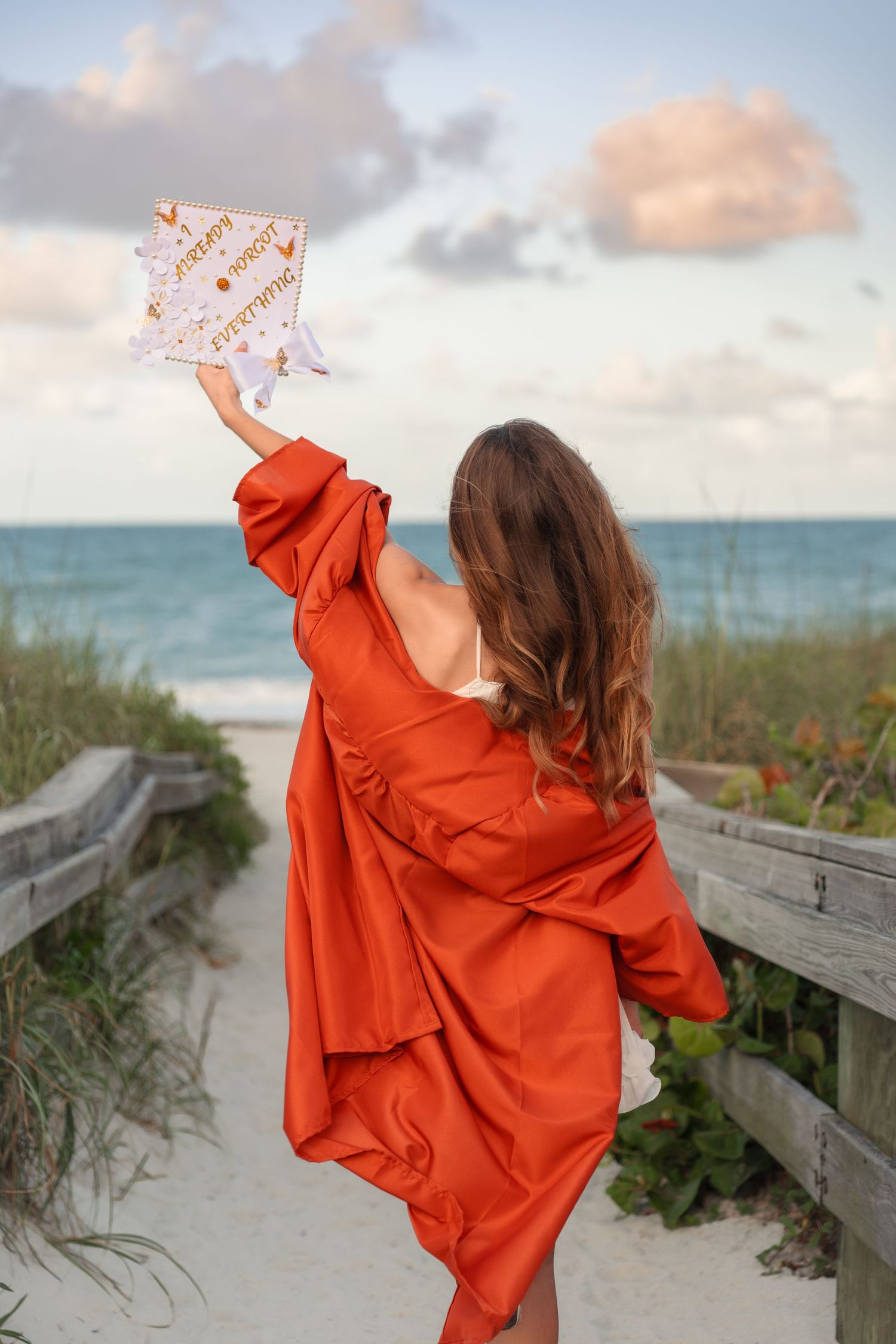 Senior graduation portraits with the beautiful sky and ocean at Melbourne Beach, Florida with cap and gown.