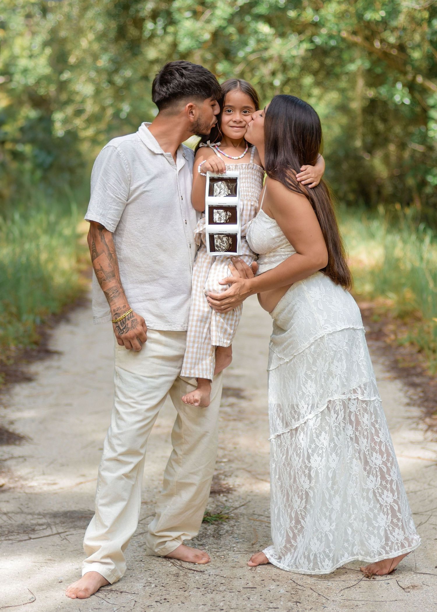 Family kissing daughter holding ultrasound announcing pregnancy during maternity photoshoot in Orlando Florida