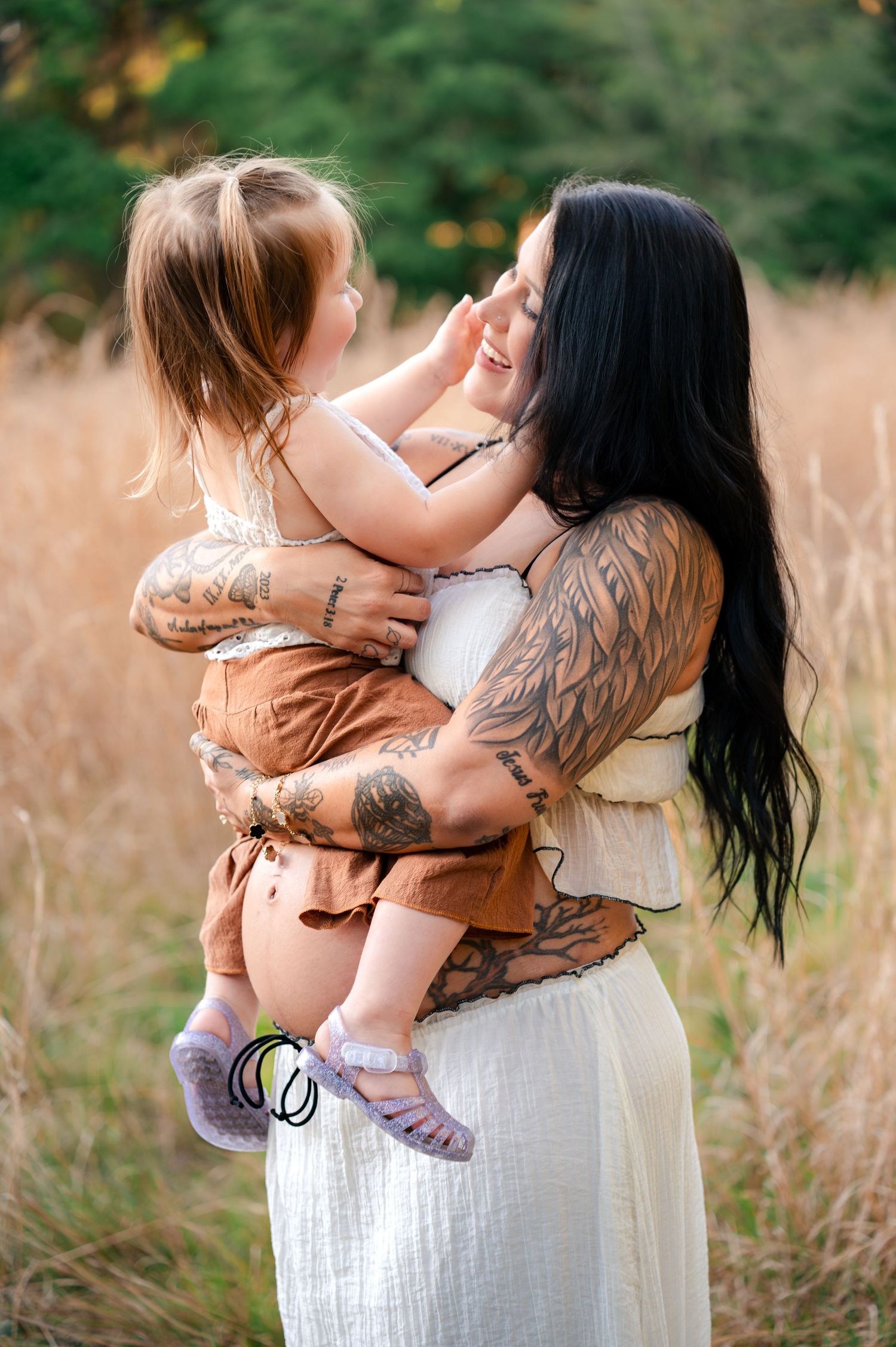 Expecting mother holding daughter during maternity session in the golden grass of Lake Runnymede Conservation Area in St Cloud Florida