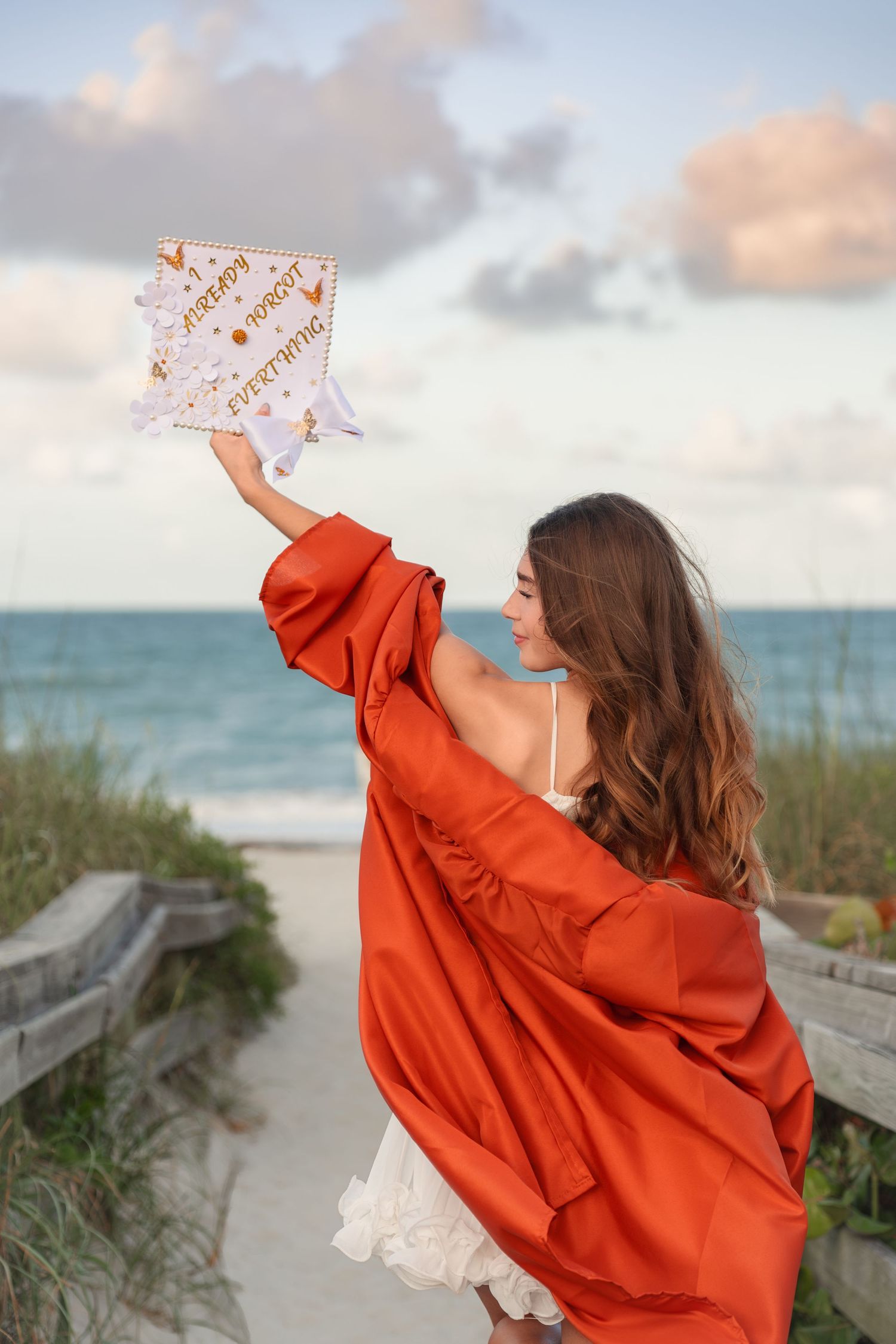 Senior graduation portraits with the beautiful sky and ocean at Melbourne Beach, Florida with cap and gown.