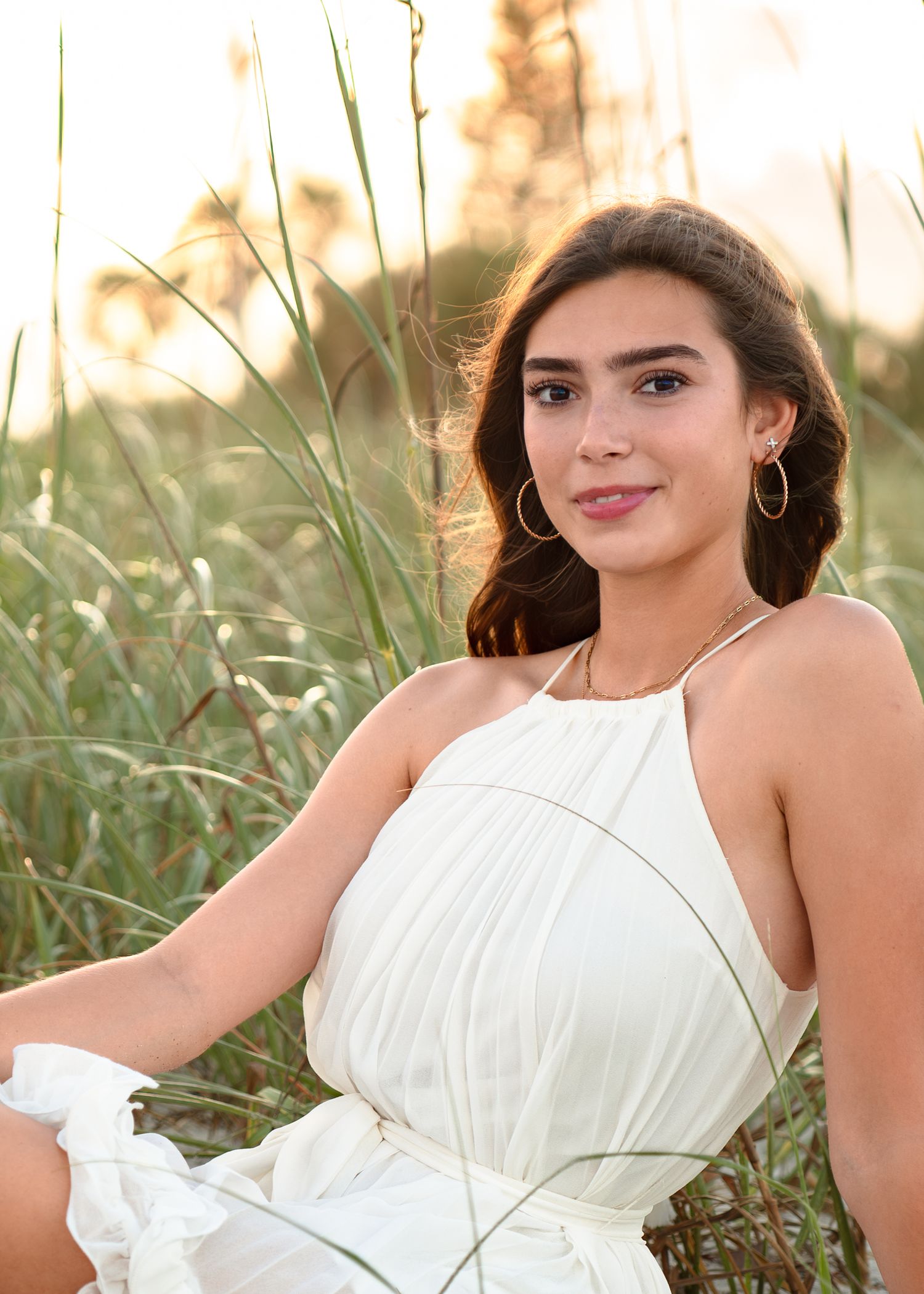 Beautiful senior graduation portrait photography featuring the sandy shoreline, dunes, and golden sunset at Melbourne Beach.