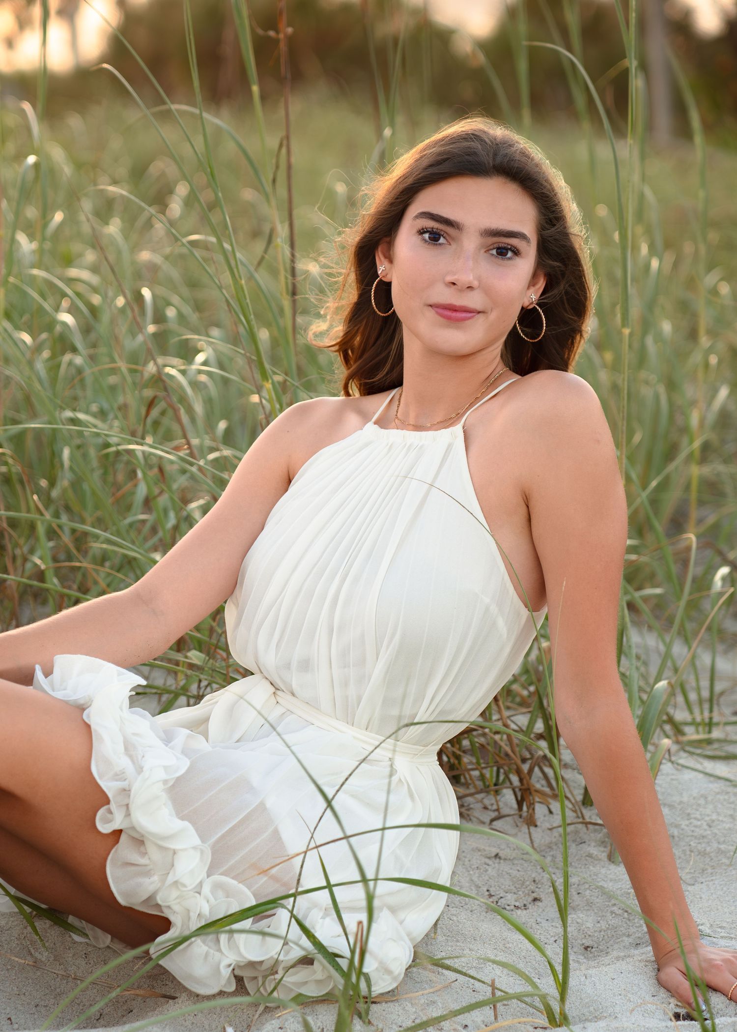 Beautiful senior graduation portrait photography featuring the sandy shoreline, dunes, and golden sunset at Melbourne Beach.