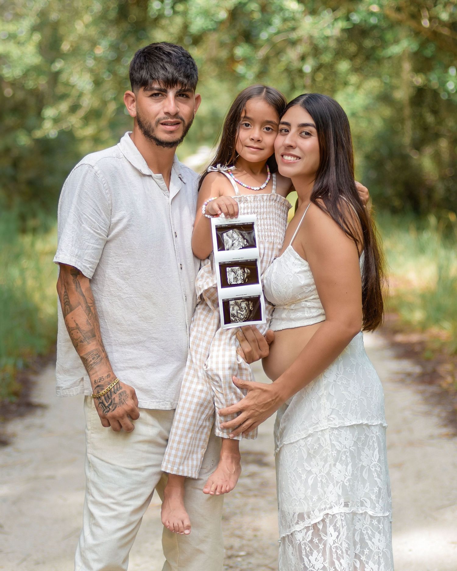 St. Cloud pregnancy announcement photo of an expecting couple holding ultrasound pictures at sunset with their daughter