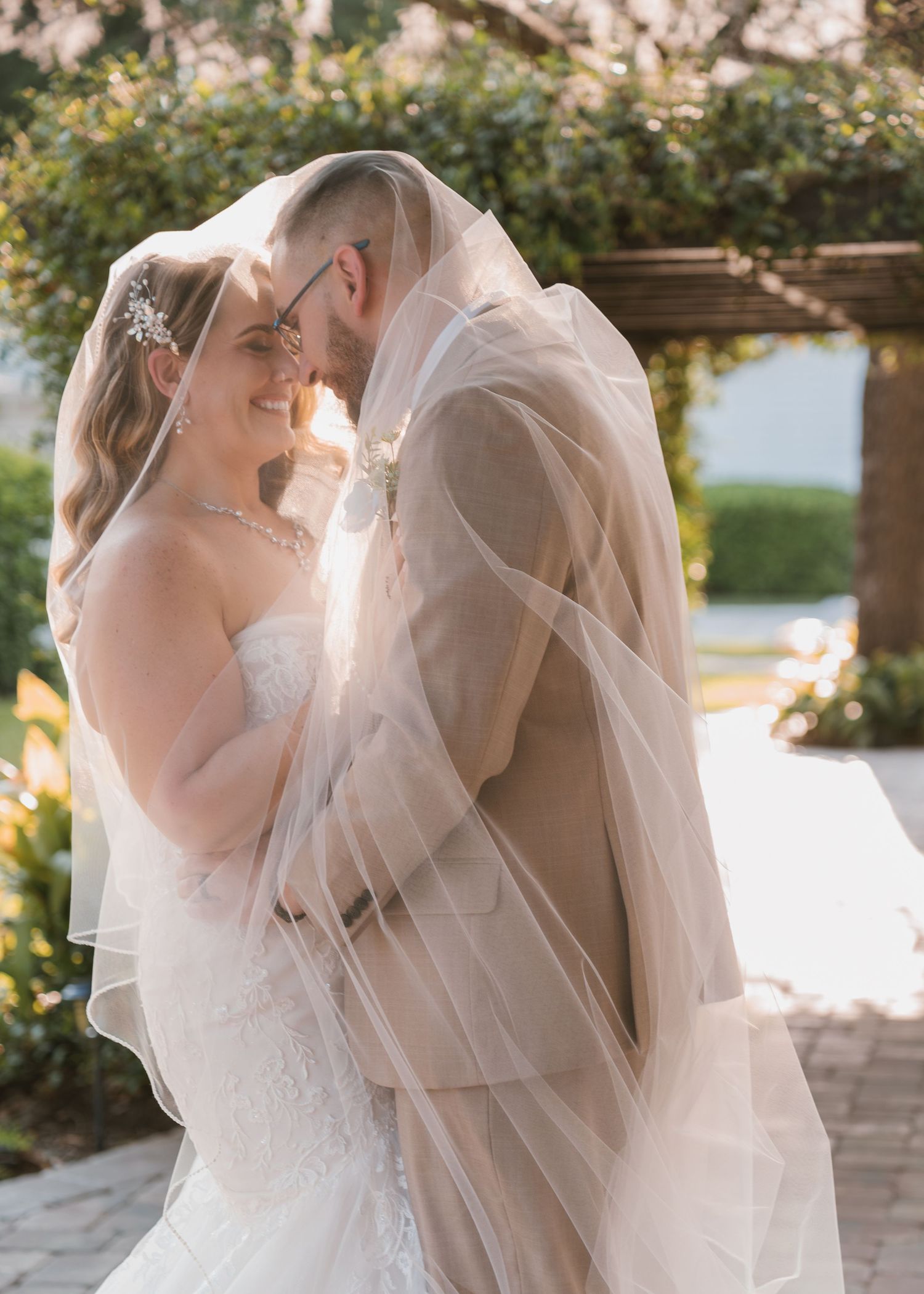Newlyweds embrace under veil surrounded by lush greenery after their ceremony at Moss Estates wedding venue in Eustis, Florida.