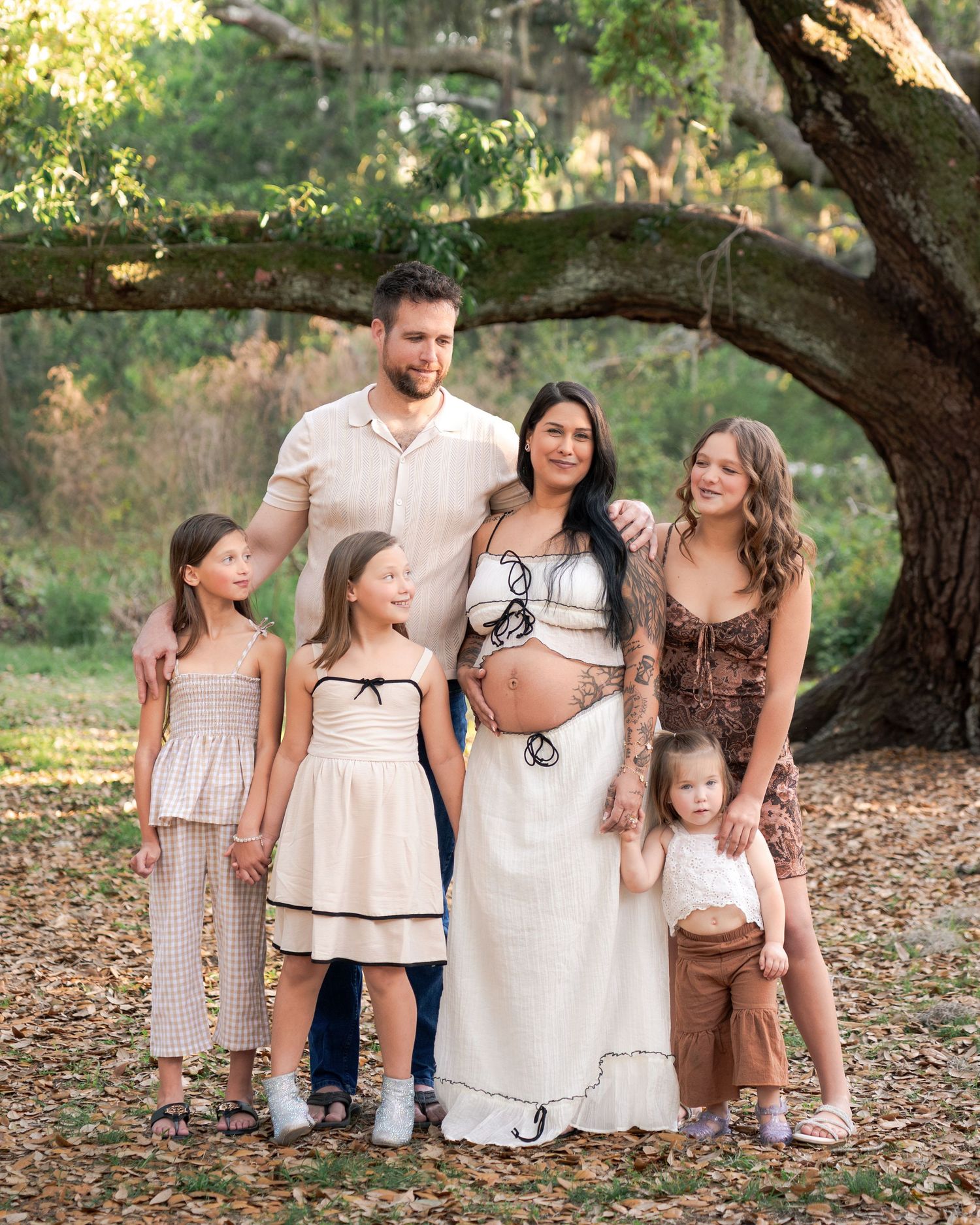 Growing family beneath the oak trees during an outdoor maternity session at Lake Runnymede Conservation Area in St. Cloud.