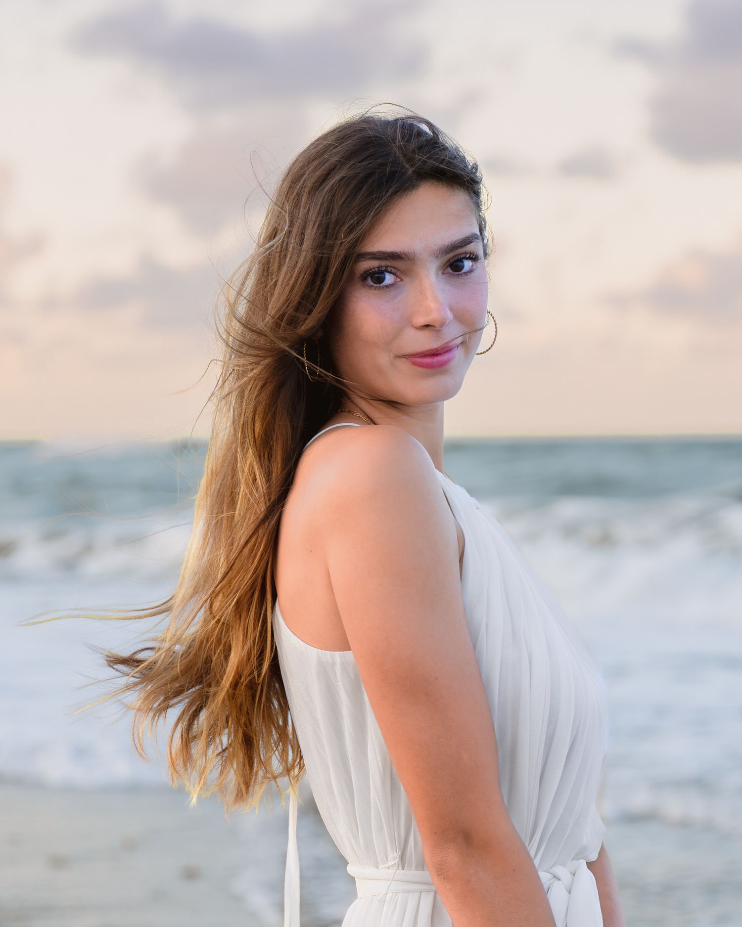Dreamy graduation portraits captured in the waves beneath the colorful pastel sunset at Melbourne Beach.