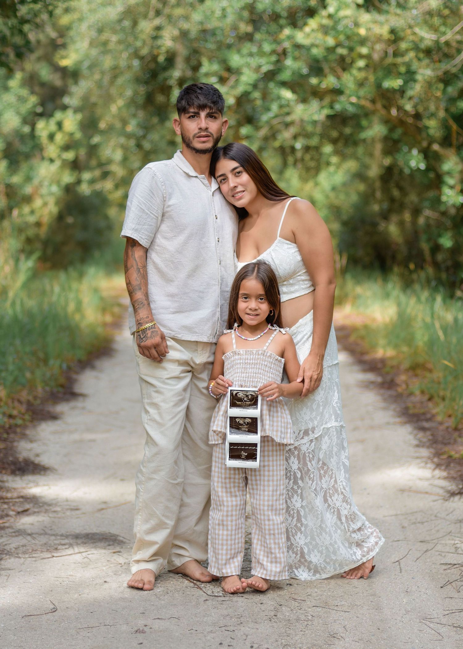 Natural light pregnancy announcement portraits in St. Cloud, Florida holding ultrasound outdoors by Orlando family photographer Erin Laine