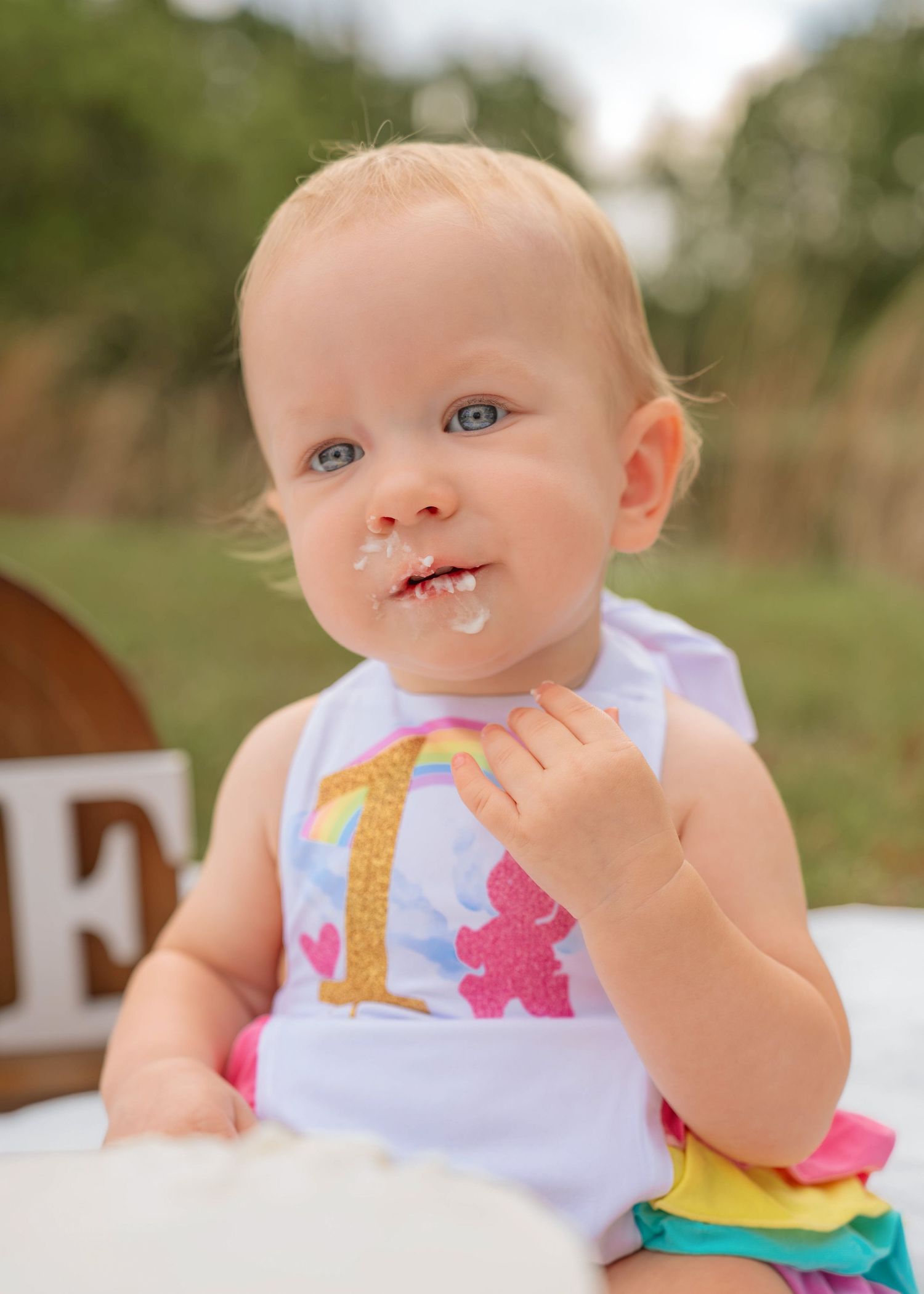 Outdoor cake smash photography documenting the fun and excitement of a first birthday celebration by St Cloud Florida family photographer