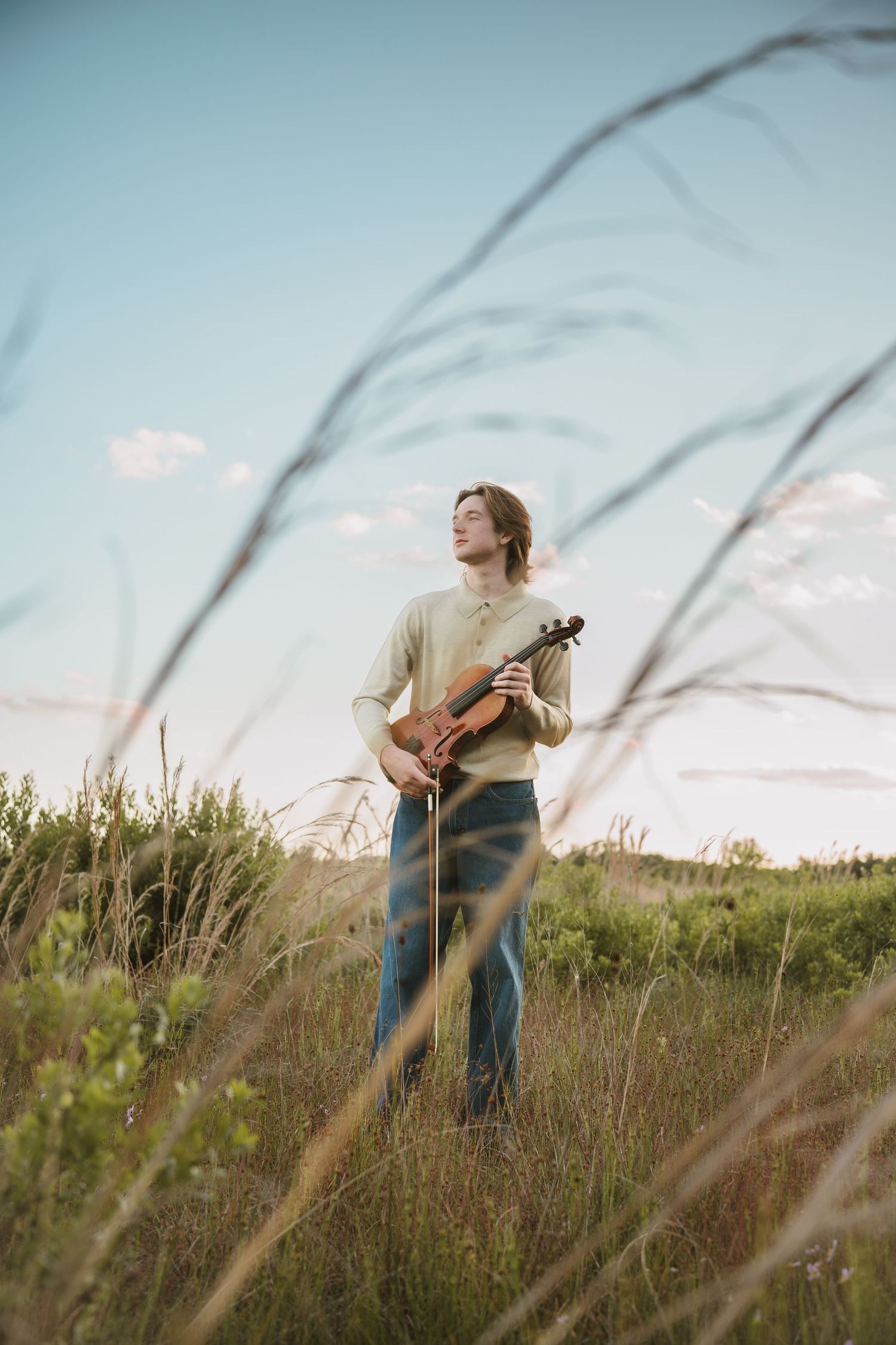 High school graduate holding his violin at sunset during portrait session at Lake Runnymede Conservation Area St Cloud Florida