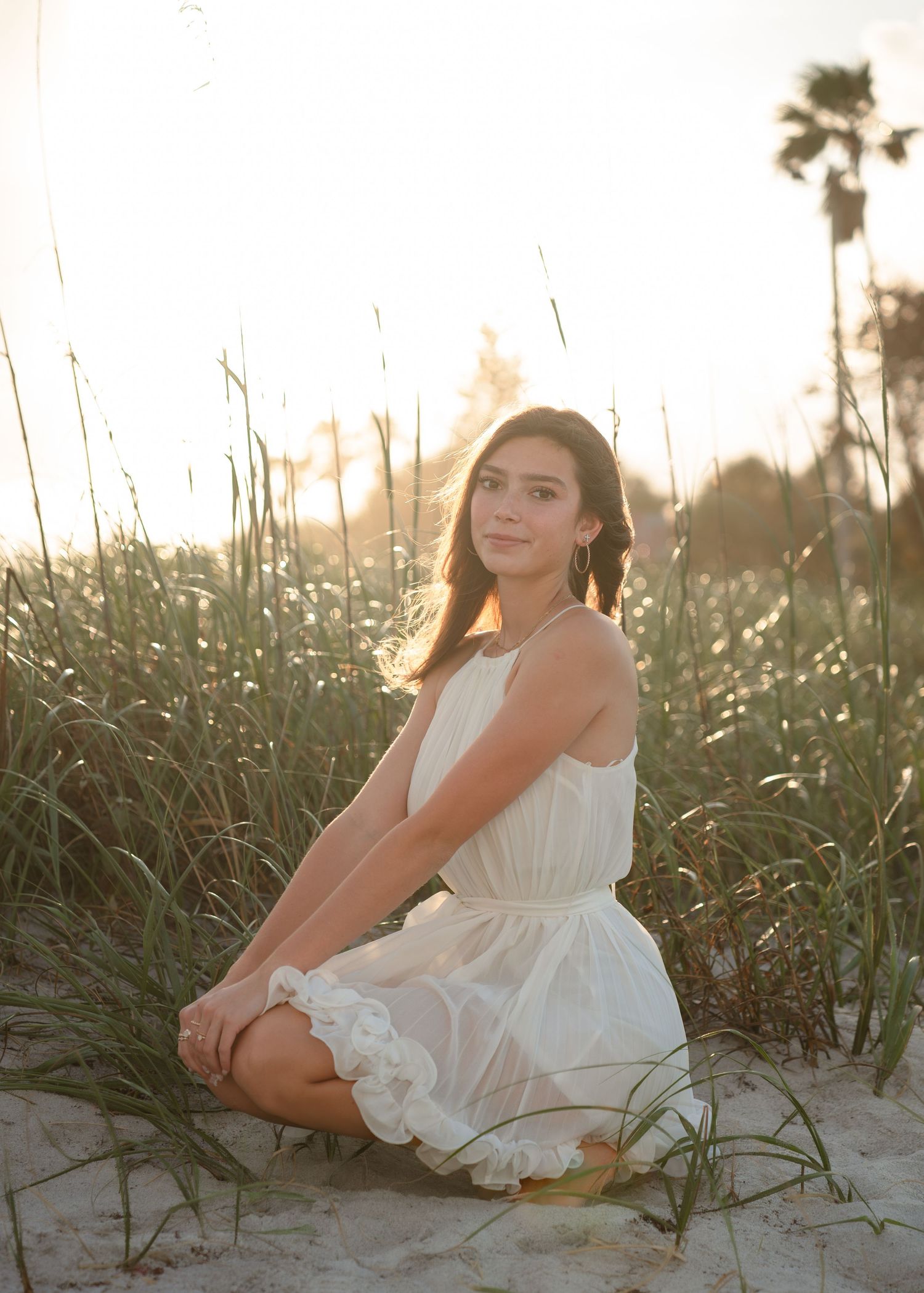 Beautiful senior graduation portrait photography featuring the sandy shoreline, dunes, and golden sunset at Melbourne Beach.