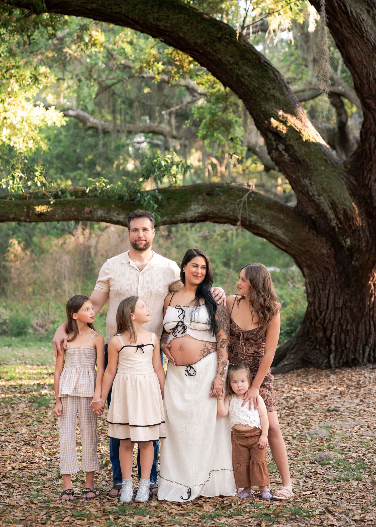 Growing family beneath the oak trees during an outdoor maternity session at Lake Runnymede Conservation Area in St. Cloud.