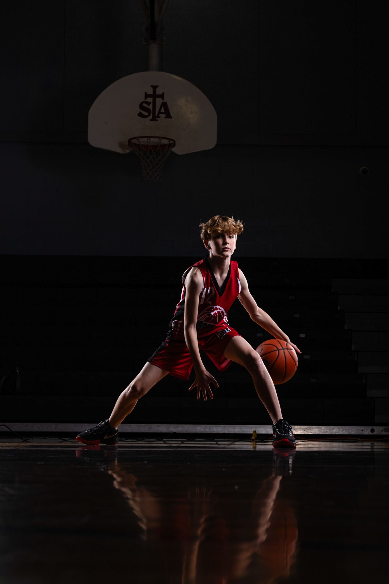 A male basketball player bouncing the ball in an action portrait using dramatic studio lighting and effects