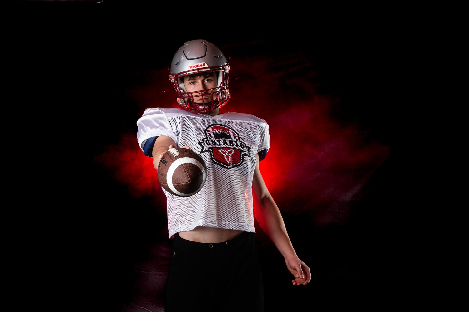 Dramatic sports media day graphic featuring a football player highlighted by creative red backlighting effects.