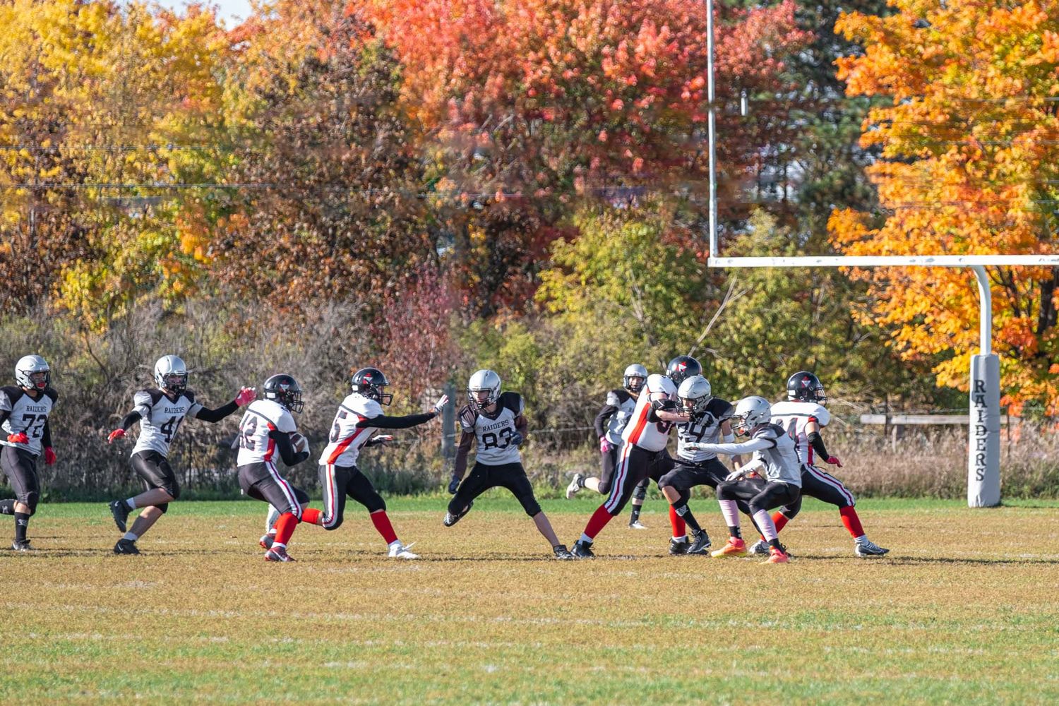 Action sports photography showing Ottawa football players in light jerseys running plays on a field.
