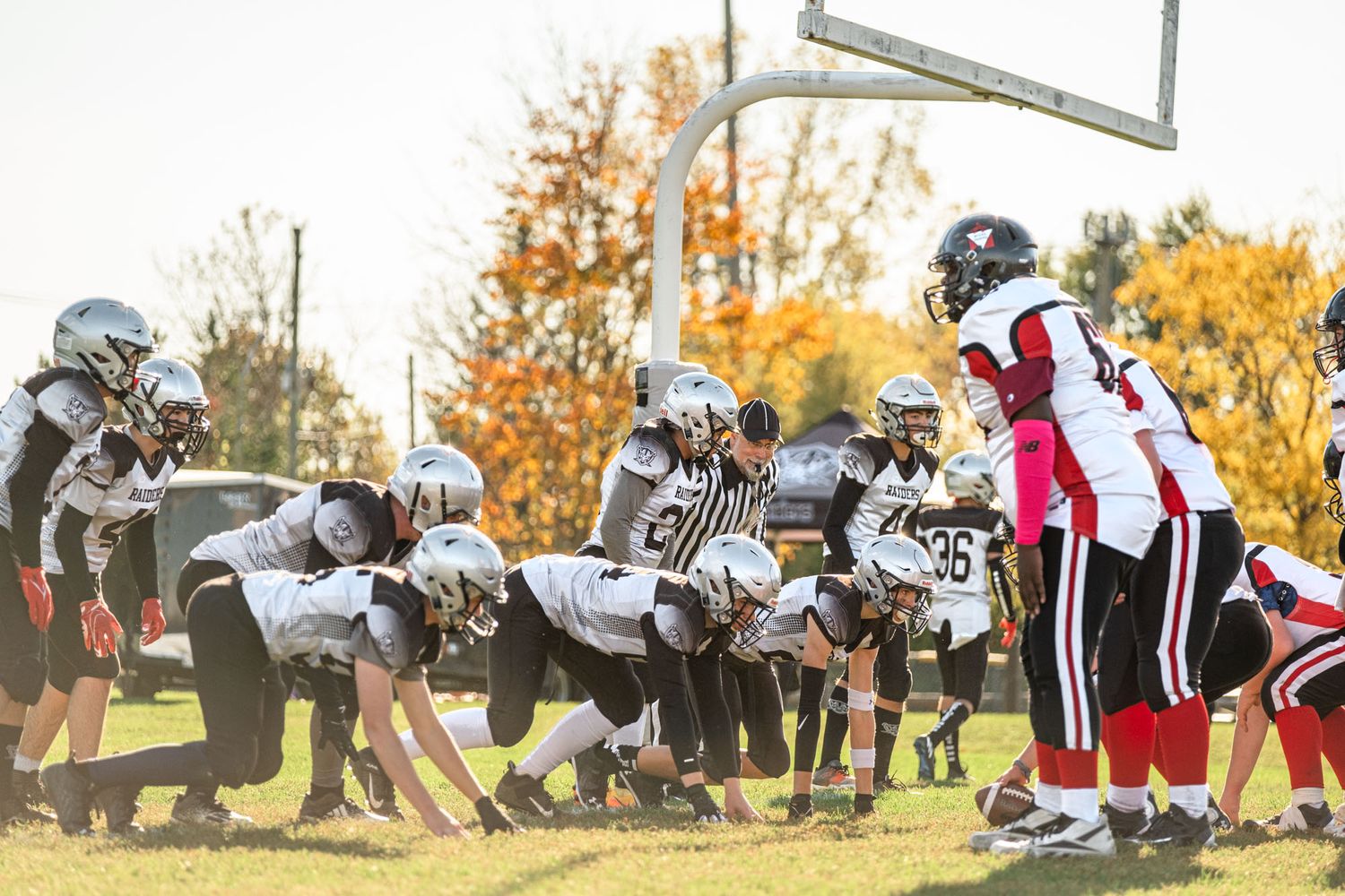 Ottawa youth football team lined up at the scrimmage line with scenic autumn trees in the background.